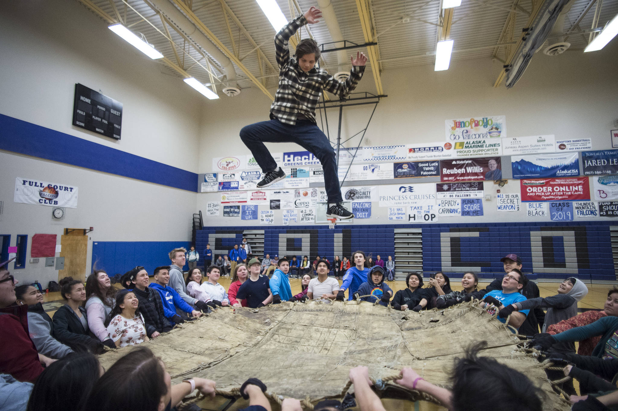 Senior Ashton Oyloe is thrown into the air by fellow students during a blanket toss demonstration at Thunder Mountain High School on Friday, March 15, 2019. (Michael Penn | Juneau Empire)