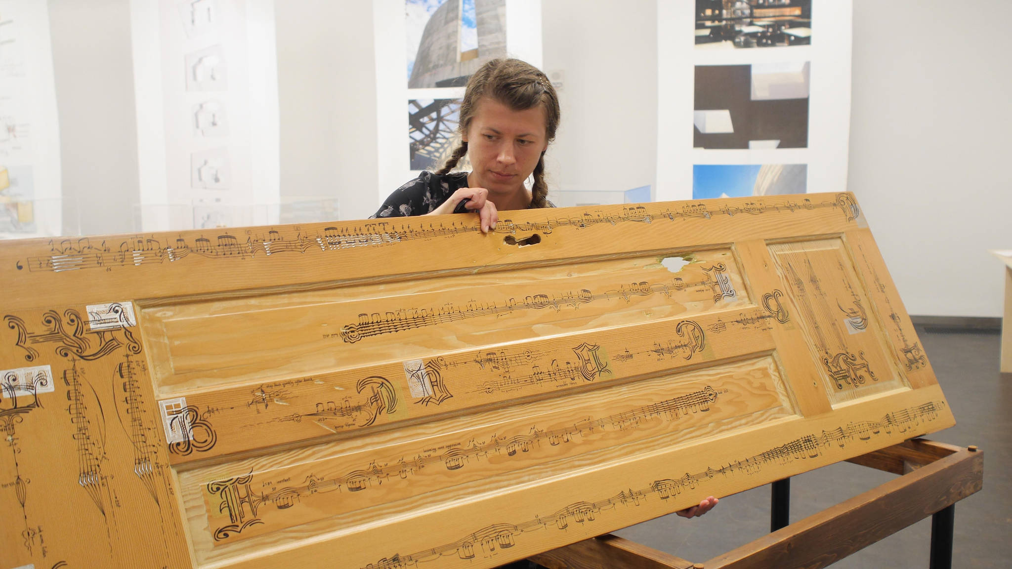 In this undated photo, Anna Pidgorna stands by her piece, “Through Closed Doors.” The arrangement of music on the door is designed so that musicians performing the piece must physically move around the door to act out dramatic dimensions of the piece. (Photo provided)