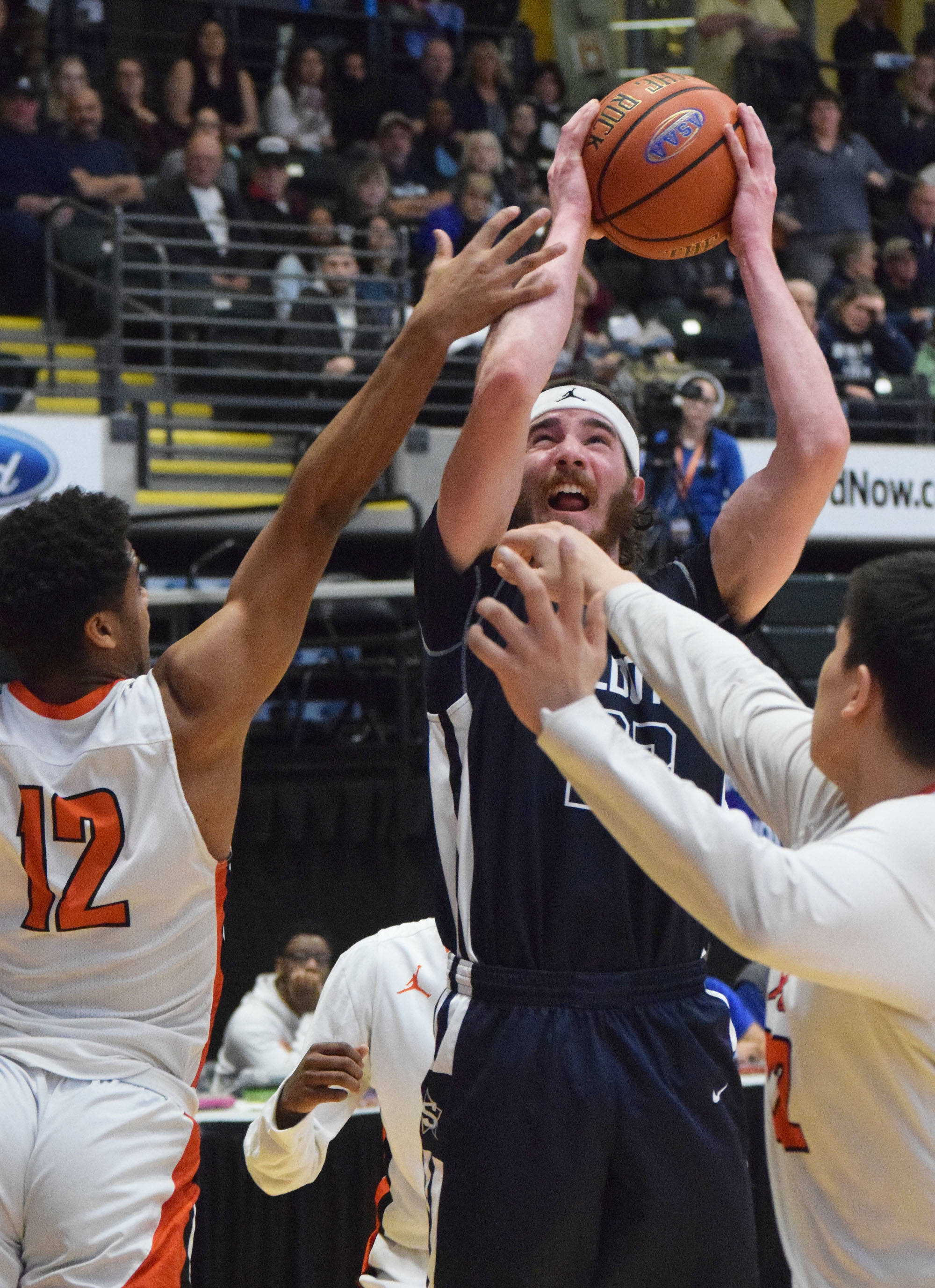 Soldotna’s David Michael (center) puts up a shot over West’s Shawn Jones (12) Thursday, Mar. 21, 2019, at the Class 4A state championship tournament at the Alaska Airlines Center in Anchorage. (Photo by Joey Klecka/Peninsula Clarion)