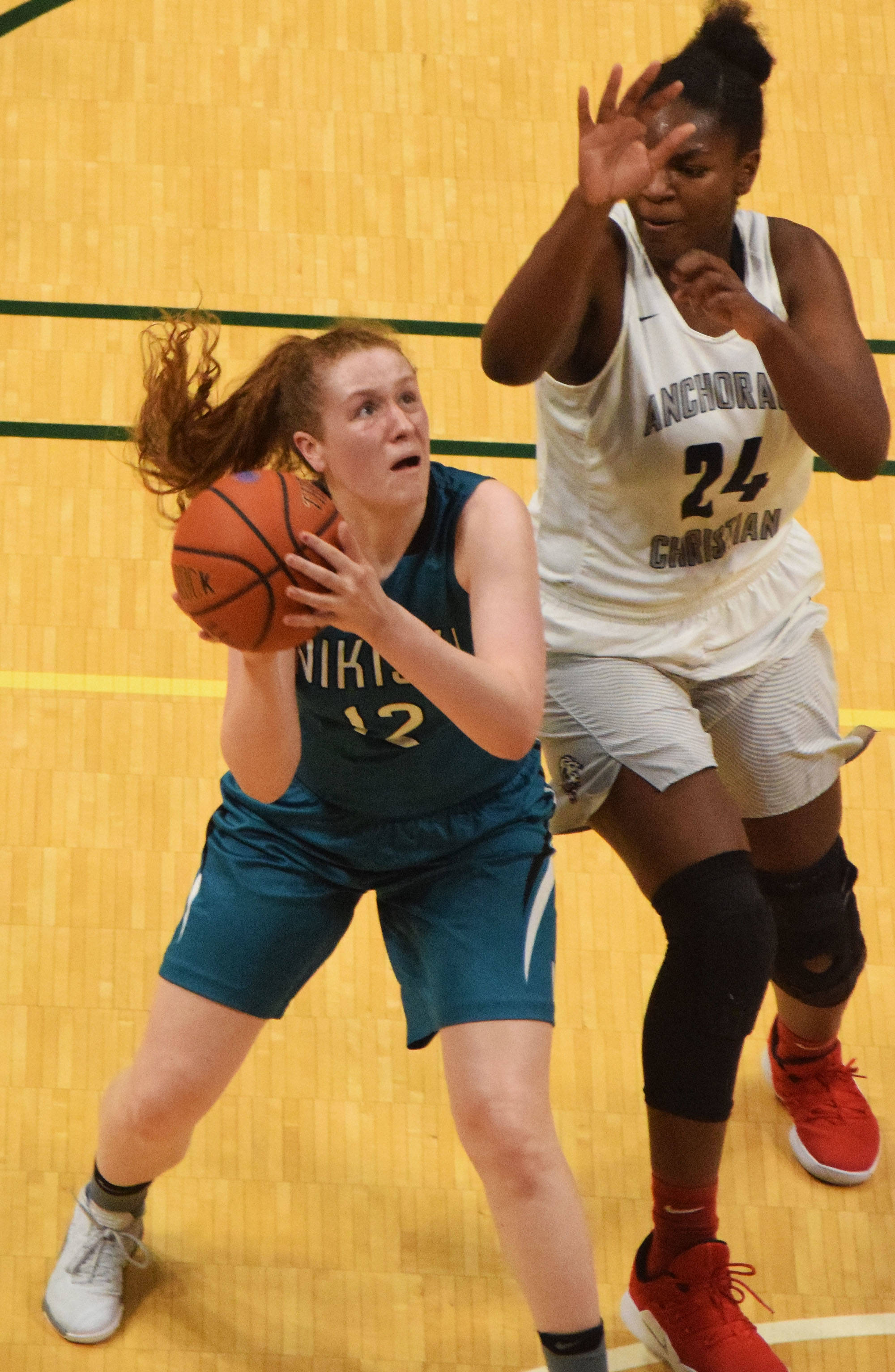 Nikiski’s Kaycee Bostic (left) drives to the rim in front of ACS’s Jordan Todd Saturday, March 23, 2019, in the Class 3A girls state basketball championship at the Alaska Airlines Center in Anchorage. (Photo by Joey Klecka/Peninsula Clarion)