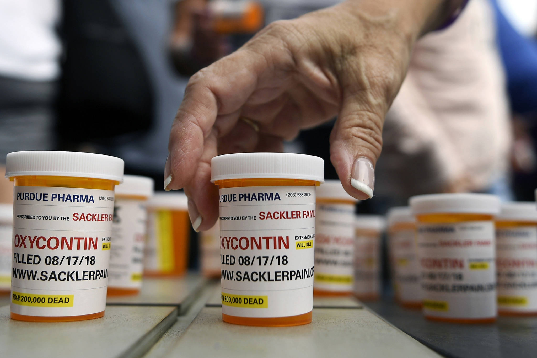 In this Aug. 17, 2018 photo, family and friends who have lost loved ones to OxyContin and opioid overdoses leave pill bottles in protest outside the headquarters of Purdue Pharma, which is owned by the Sackler family, in Stamford, Connecticut. (Jessica Hill | Associated Press File)