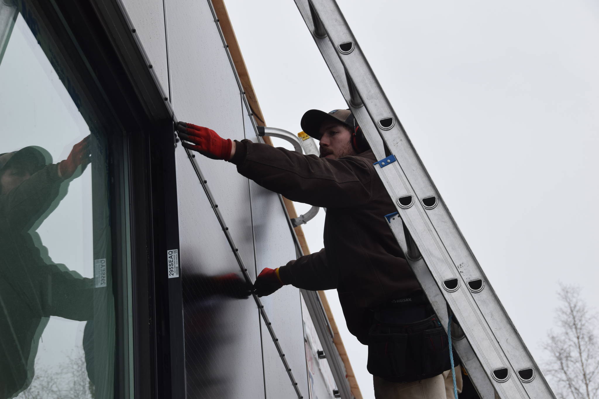 A technician from Anchorage Solar installs vertical solar panels at the new location for River City Books in Soldotna on Saturday. (Photo by Brian Mazurek/Peninsula Clarion)