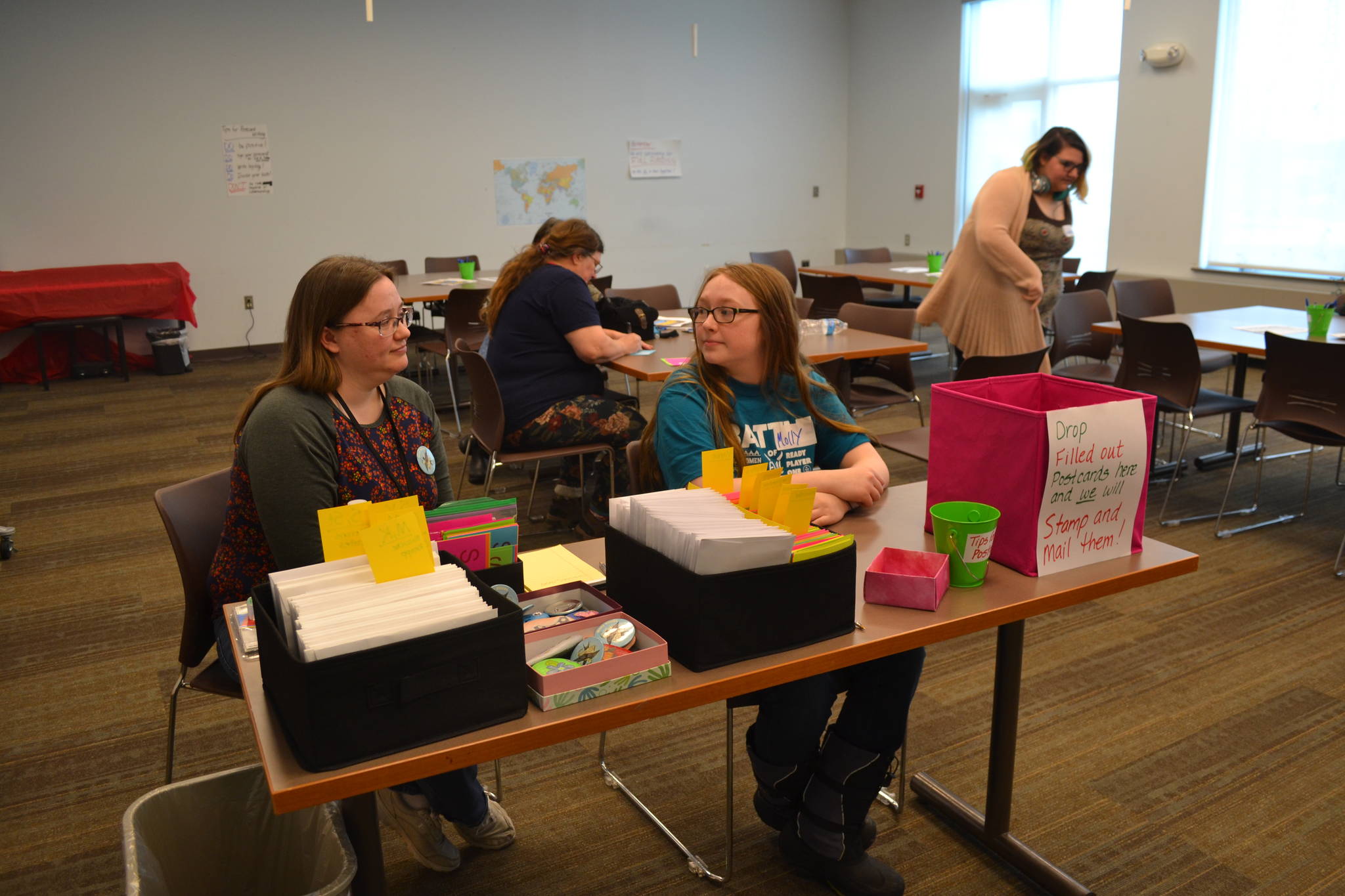 Eva Knutson and her daughter Molly Koski help host a postcard-writing event that helps students and community members to reach out to their local lawmakers in regards to Gov. Mike Dunleavy’s recently proposed budget cuts, on Wednesday, March 20, 2019, at the Soldotna Public Library in Soldotna, Alaska. (Photo by Victoria Petersen/Peninsula Clarion)