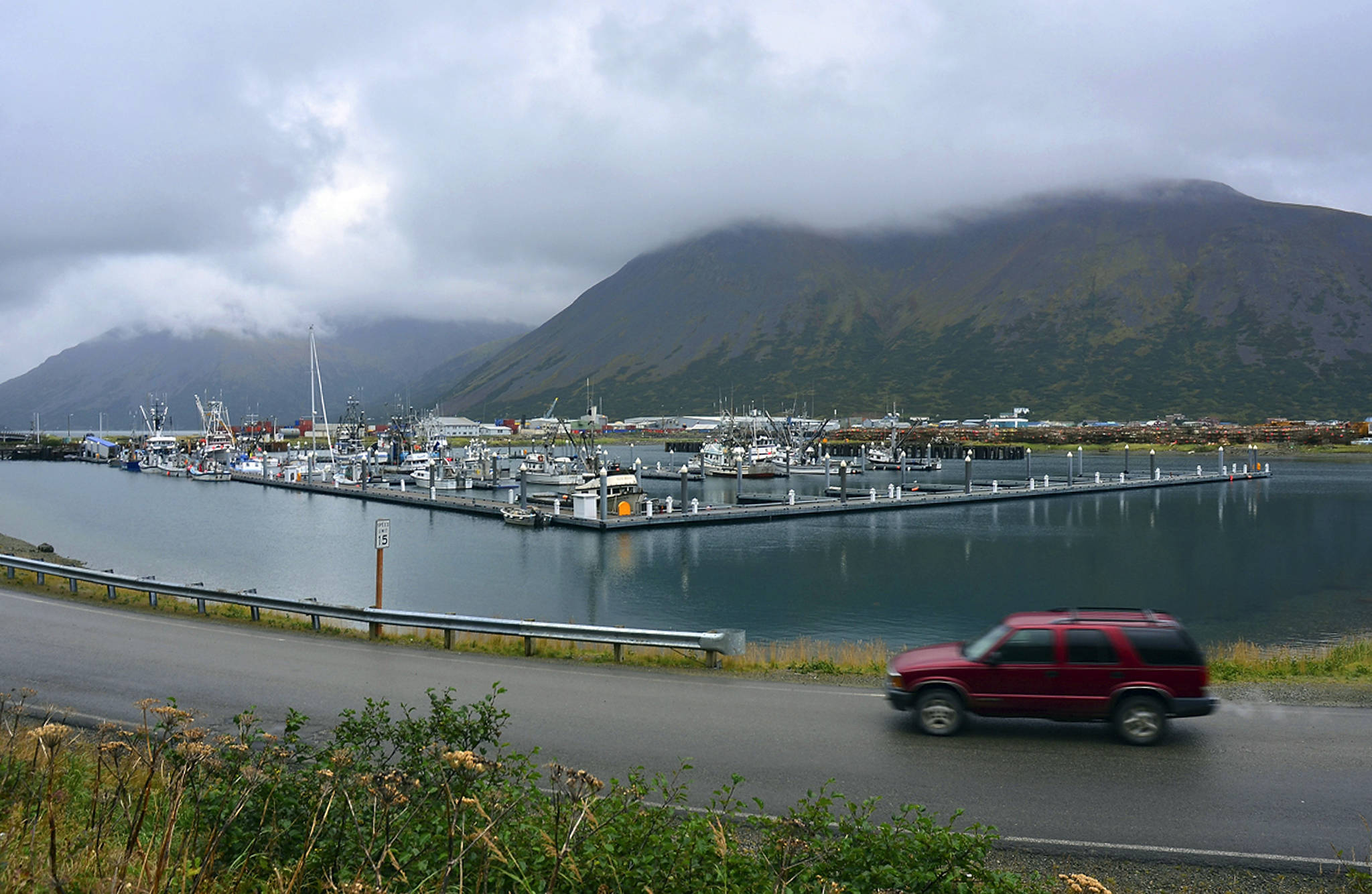 In this Sept. 23, 2013, file photo, a driver passes a small boat harbor in King Cove, Alaska. A federal court judge says Trump administration plans for a road through a national wildlife refuge in Alaska violates federal law. The order Friday, March 29, 2019 by U.S. District Court Judge Sharon Gleason halts plans for a road through the Izembek National Wildlife Refuge near the tip of the Alaska Peninsula. The refuge encompasses internationally recognized habitat for migrating waterfowl. (James Brooks/Kodiak Daily Mirror via AP, File)