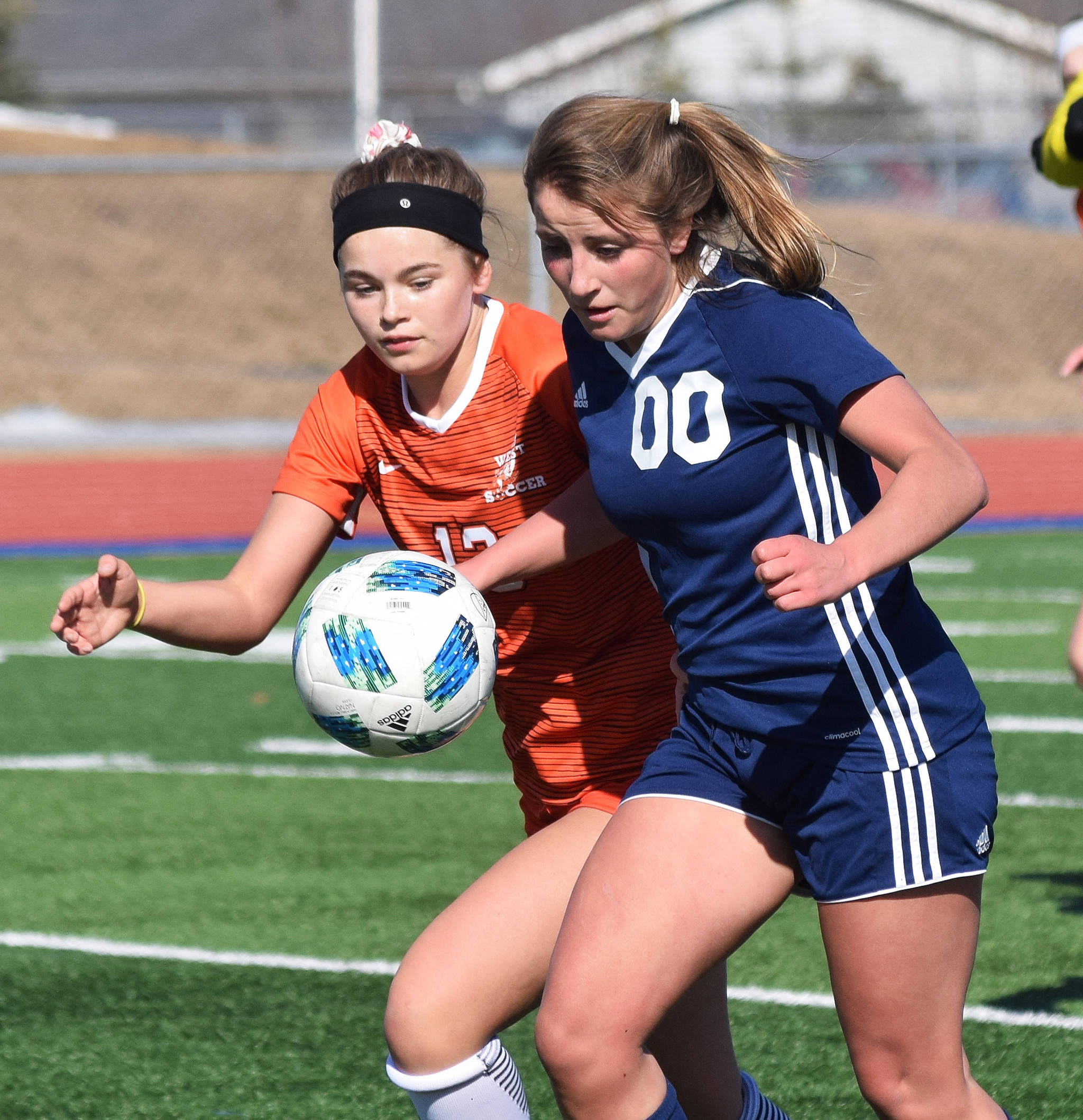 Soldotna’s Ryann Cannava (00) battles for the ball with West’s Skyler Helgeson Friday, April 5, 2019, in a nonconference contest at Soldotna High School. (Photo by Joey Klecka/Peninsula Clarion)