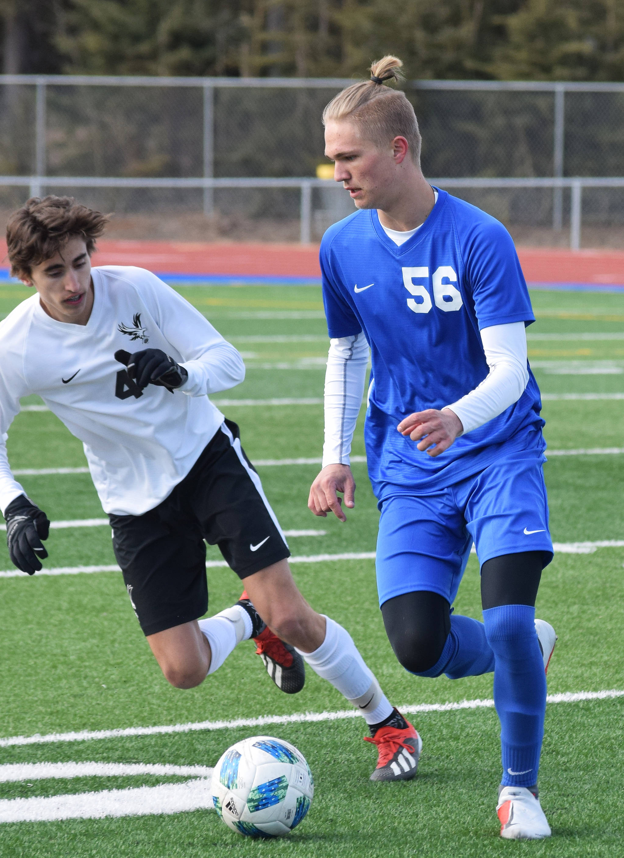 Soldotna senior Kaleb Swank dribbles around a West Anchorage defender Friday, April 5, 2019, at Soldotna’s Justin Maile Field. (Photo by Joey Klecka/Peninsula Clarion)