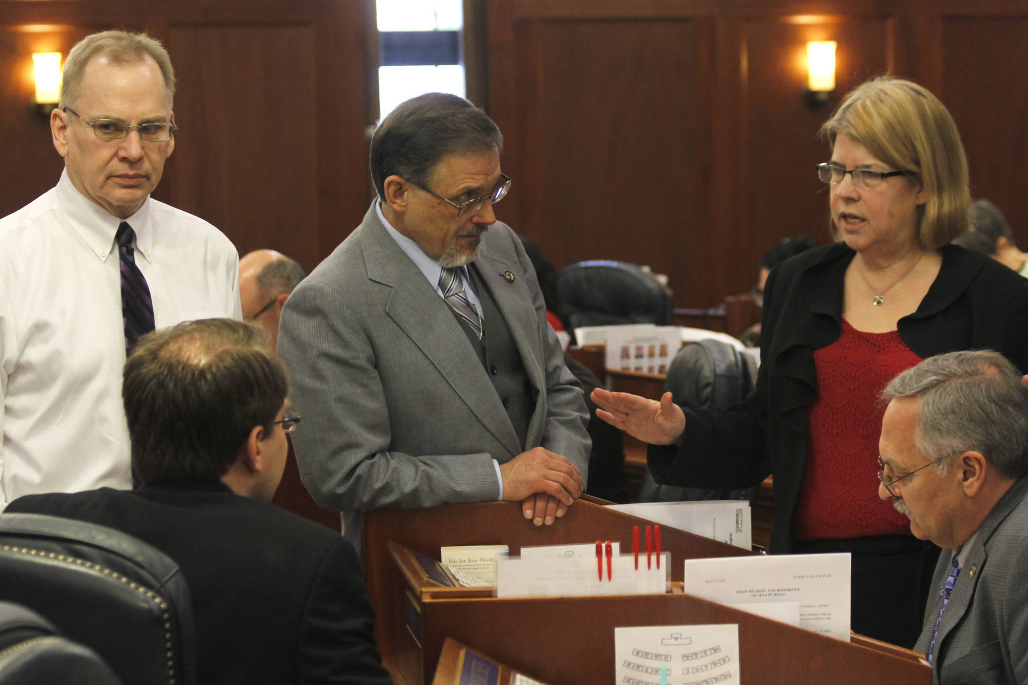 Rep. Tammie Wilson, right, speaks to other representatives on the House of Representatives floor on Wednesday. (Alex McCarthy | Juneau Empire)