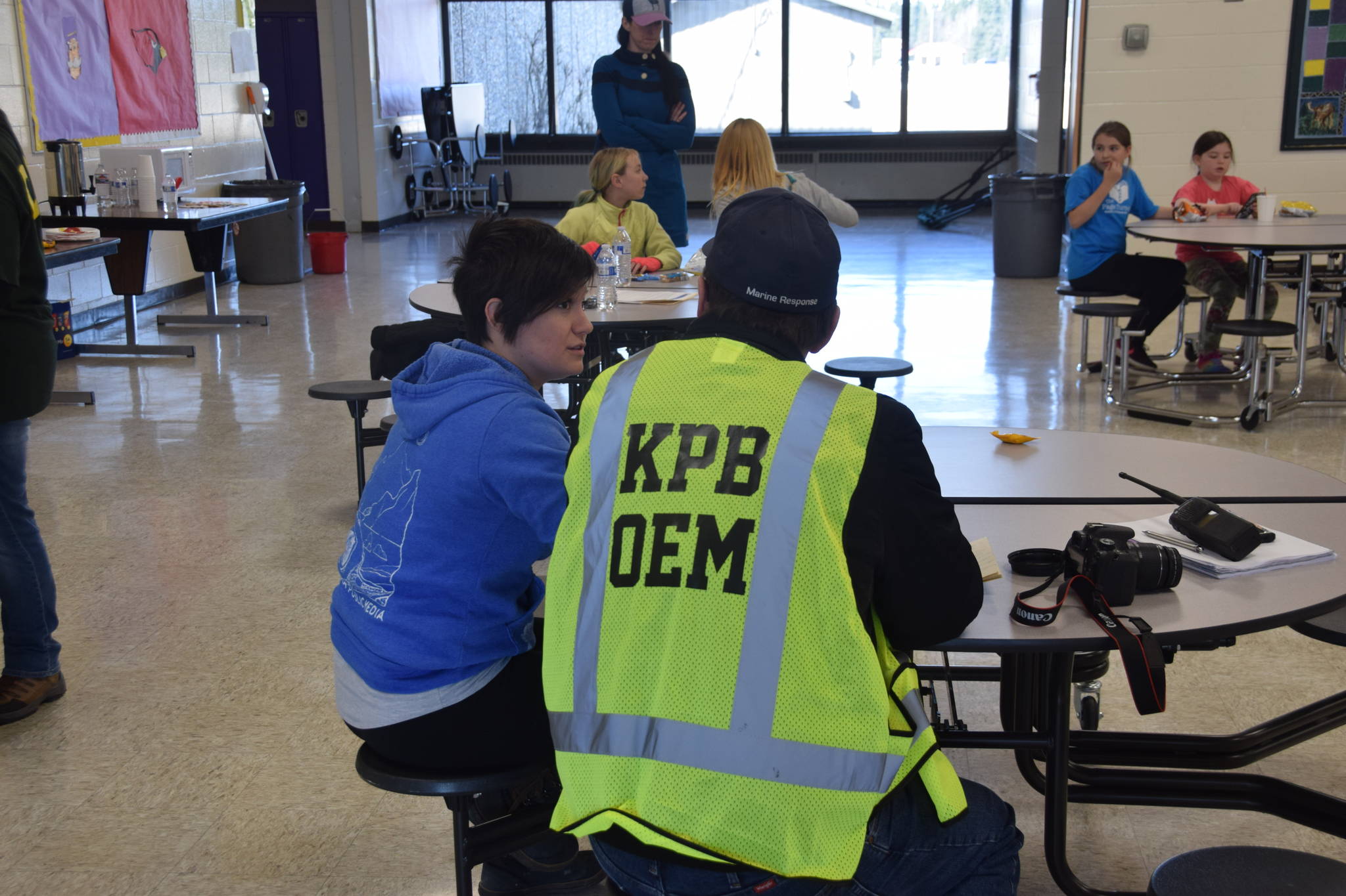 An OEM employee sits with an “evacuee” at Kenai Middle School in Kenai, Alaska during OEM’s Alaska Shield 2019 program on Saturday, April 13, 2019. (Photo by Brian Mazurek/Peninsula Clarion)