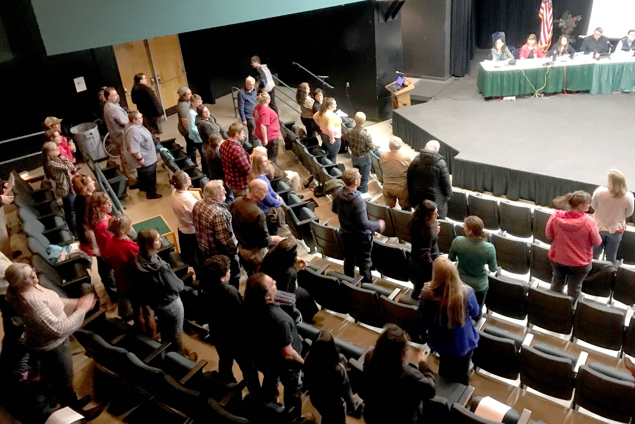 Audience members stand to show their support of the Kenai Peninsula Borough School District during the Kenai Peninsula Borough Assembly meeting Tuesday, April 16 at Seward High School in Seward, Alaska. (Photo by Kat Sorensen/Peninsula Clarion)