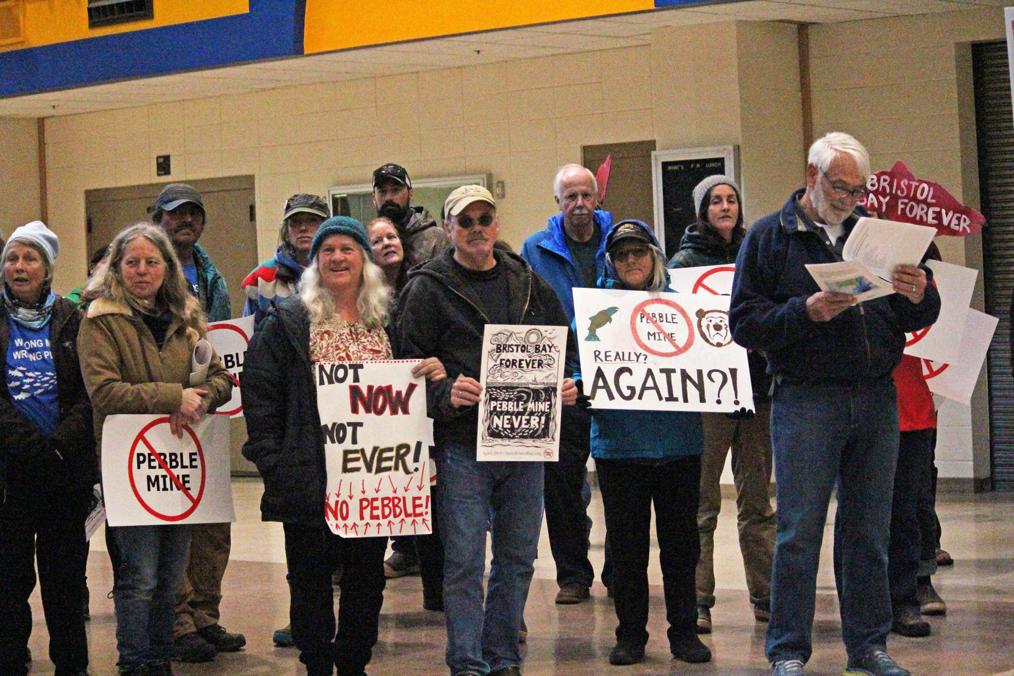 Protesters stand in the Homer High School Commons at the end of a rally held by Cook Inletkeeper at the same time as a April 11, 2019 public hearing hosted by the Army Corps of Engineers to take comments on the Draft Environmental Impact Statement for the proposed Pebble Mine, held at the high school in Homer, Alaska. The protesters marched from their rally outside the school into the commons with the intention of marching into the hearing. (Photo by Megan Pacer/Homer News)