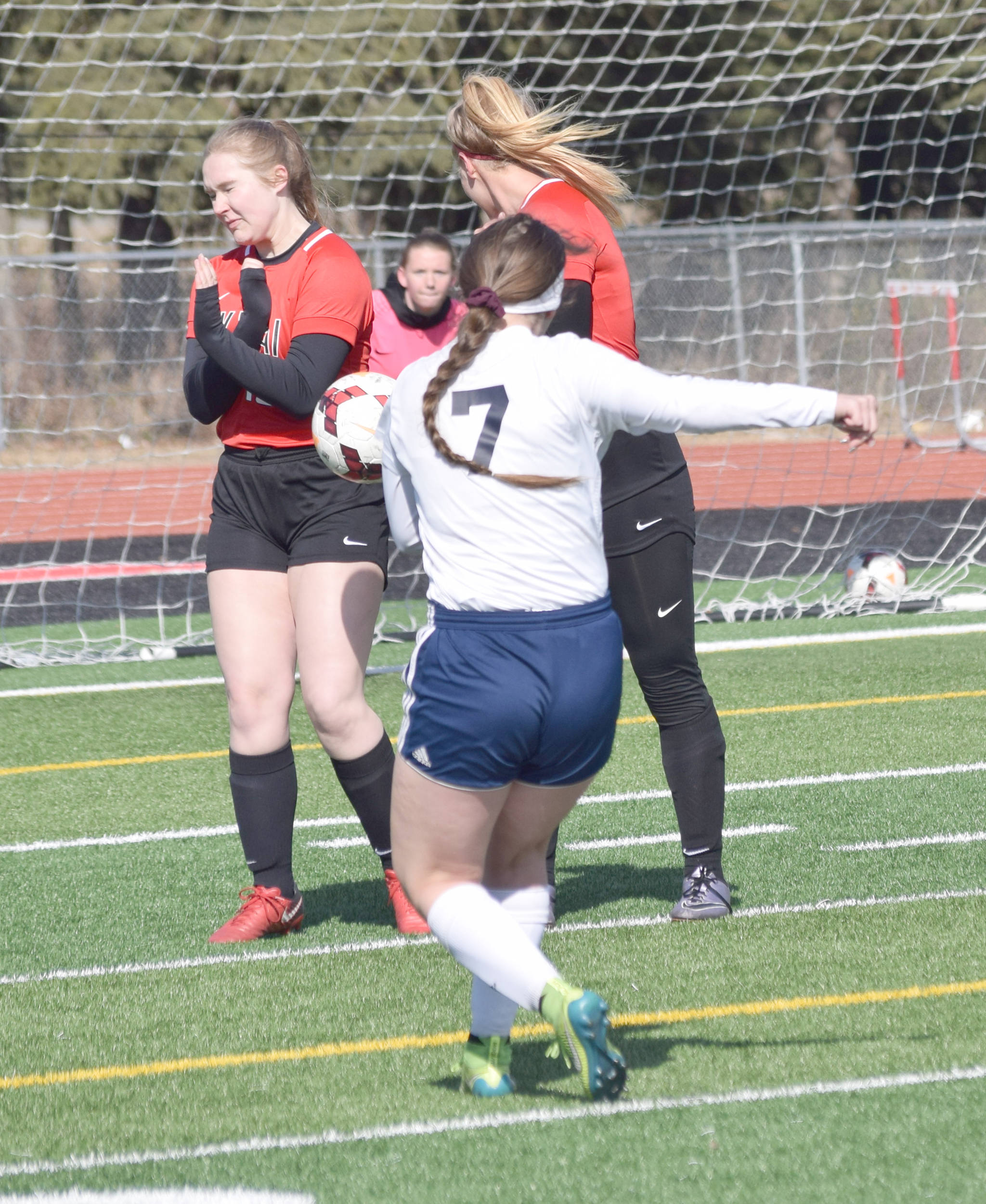 Julia Hanson of Kenai Central blocks the shot of Soldotna’s Journey Miller on Monday, April 22, 2019, at Ed Hollier Field at Kenai Central High School in Kenai, Alaska. Anya Danielson is in the wall with Hanson, while Kailey Hamilton is in net. (Photo by Jeff Helminiak)