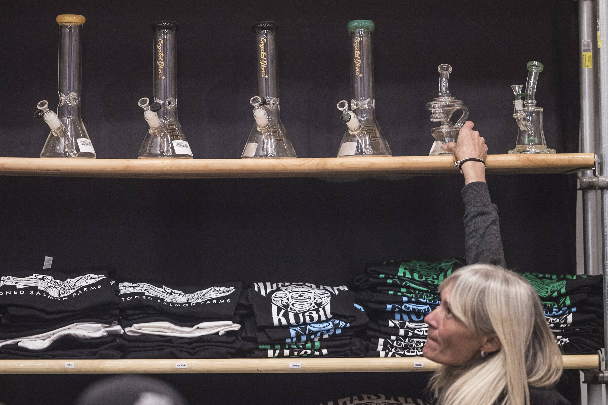 Lori Martin, an employee at the Alaskan Kush Company, straightens their display of water pipes on Tuesday, April 16, 2019. (Michael Penn | Juneau Empire)