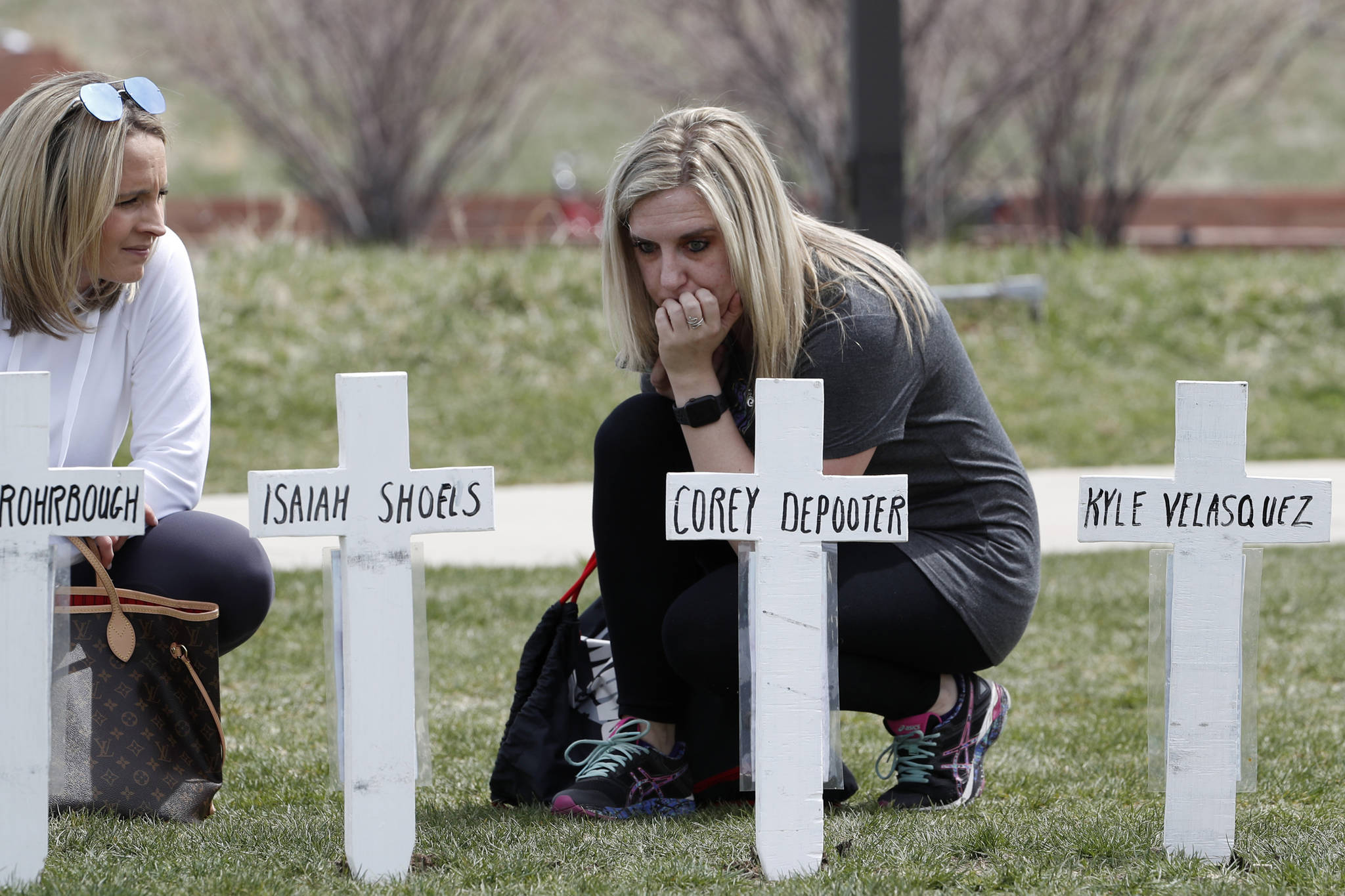 Cassandra Sandusky, right, a graduate of Columbine High School, pauses with her friend, Jennifer Dunmore, at a row of crosses bearing the names of the victims of the attack at the school 20 years ago before a program for the victims Saturday, April 20, 2019 in Littleton, Colorado. (David Zalubowski | Associated Press)