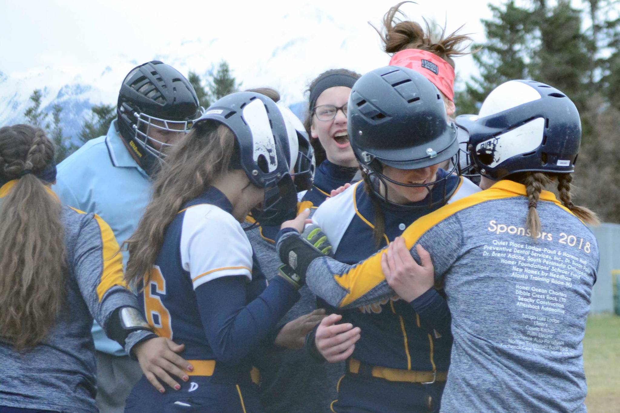 Homer High School Mariners softball batter Grace Godfrey gets a hug from her teammates after two other players scored on her hit on Tuesday, April 30, 2019, against Soldotna High School at Jack Gist Park in Homer, Alaska. (Photo by Michael Armstrong/Homer News)