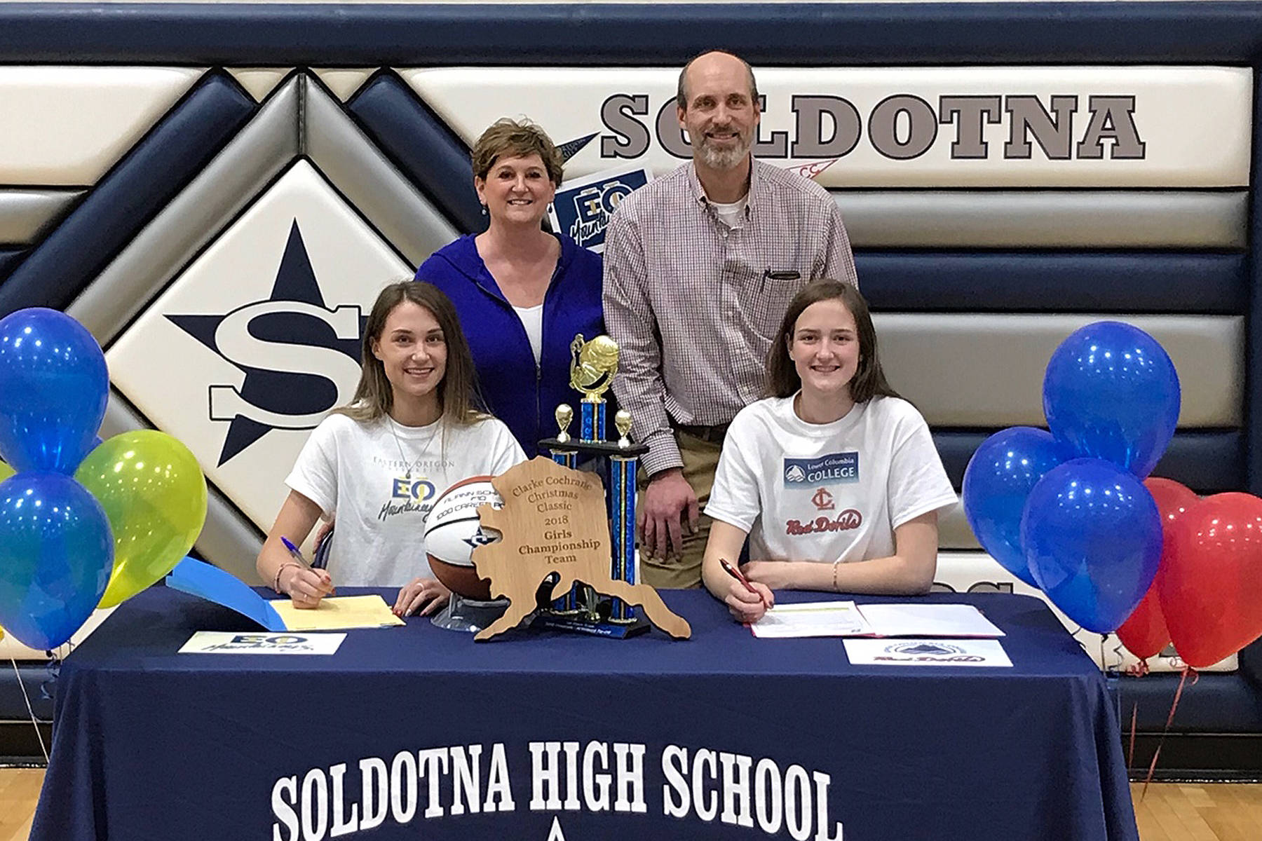 Soldotna seniors Aliann (bottom left) and Danica Schmidt (bottom right) sign their letters of intent to play college basketball Thursday at Soldotna High School, with parents, Margaret and Curtis Schmidt, by their side. (Photo provided by Kyle McFall)