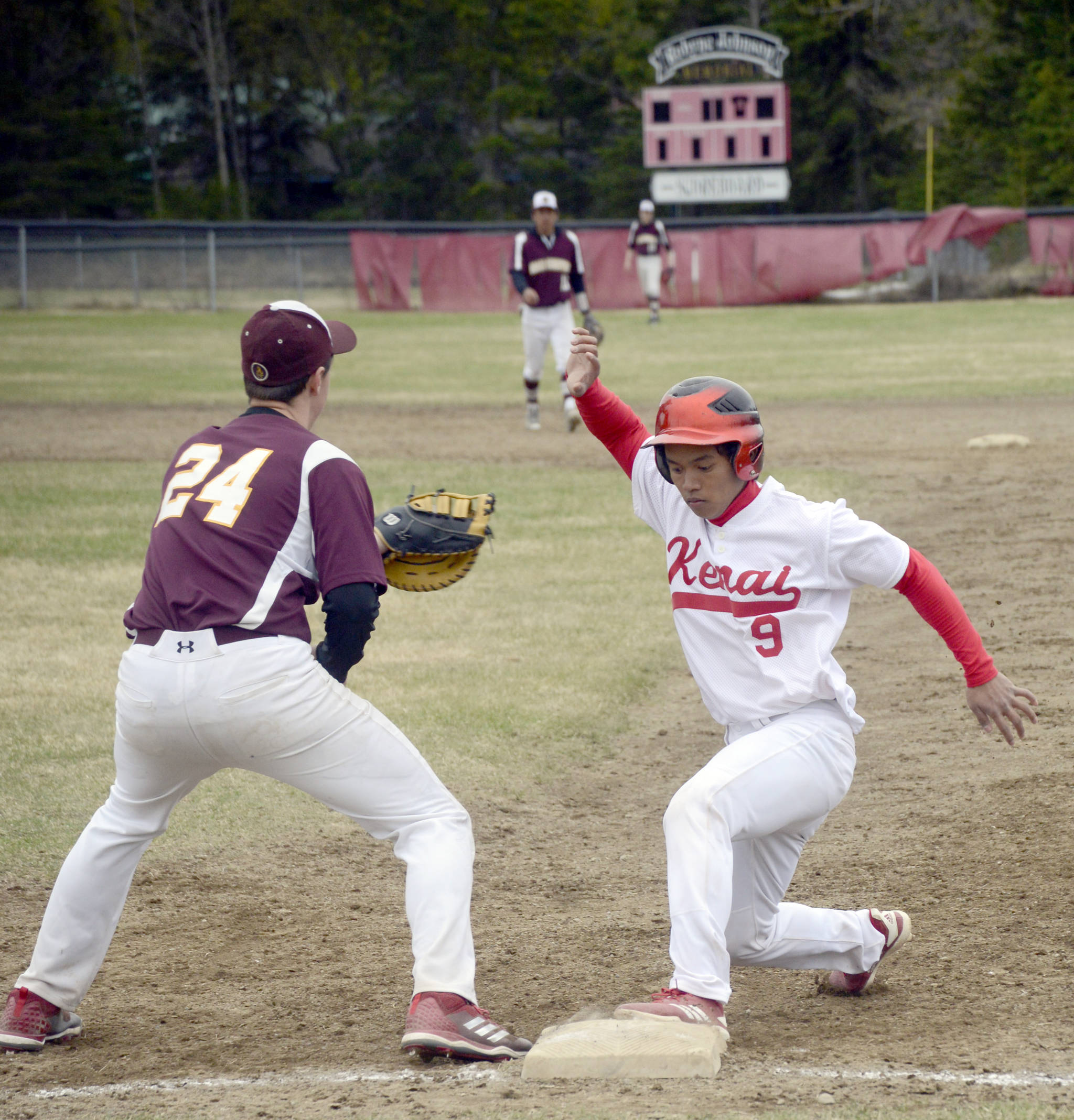 Kenai Central’s Harold Ochea gets back to first base before Grace Christian first baseman Steven Brown can apply the tag Friday, May 10, 2019, at the Kenai Little League fields in Kenai, Alaska. (Photo by Jeff Helminiak/Peninsula Clarion)