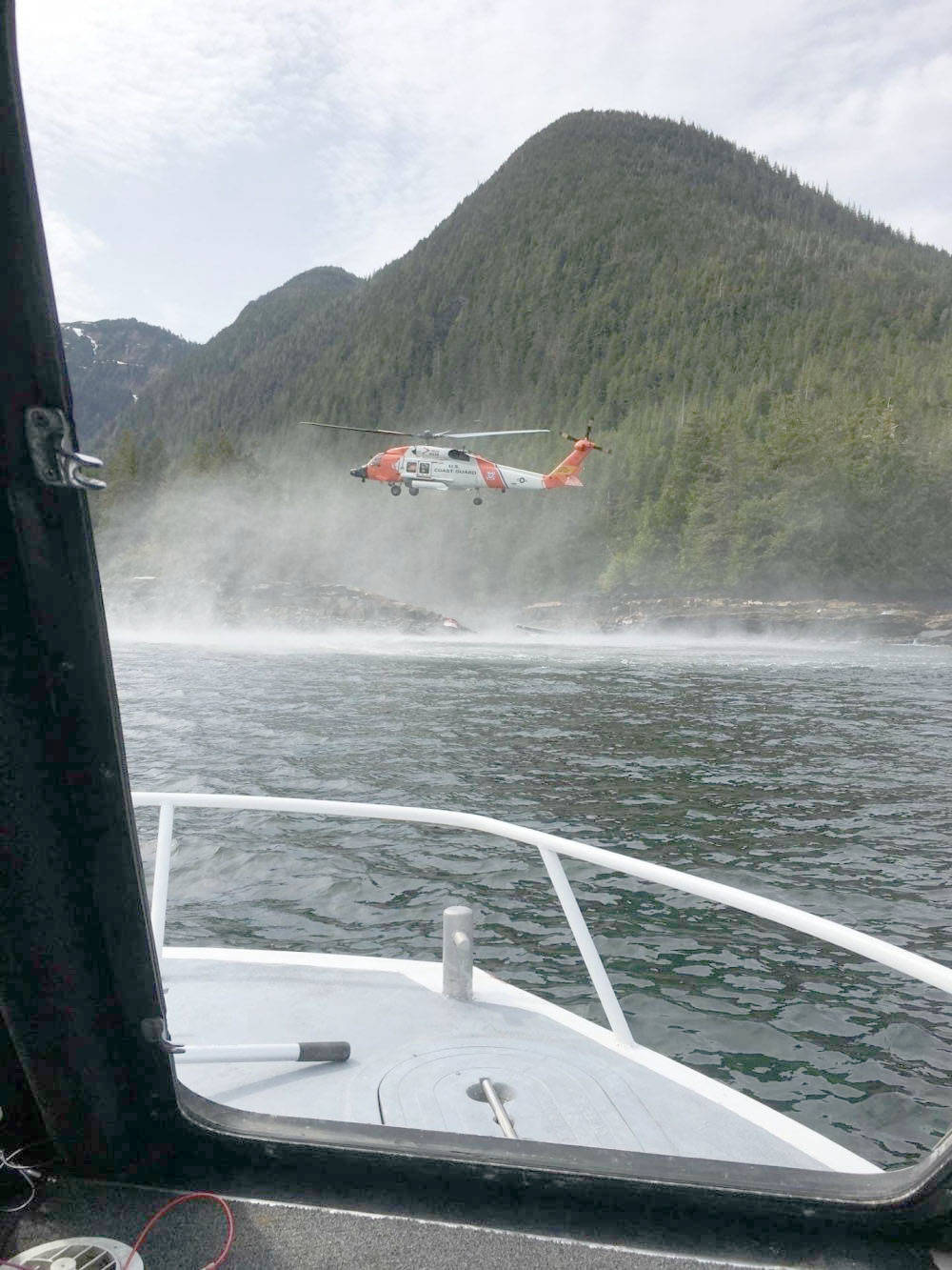 A Coast Guard Air Station Sitka MH-60 Jayhawk helicopter crew hovers while searching for a survivor from a report of two aircraft colliding in the vicinity of George Inlet near Ketchikan, Tuesday. Ten survivors of the crash had reportedly swam to shore and were rescued by Coast Guard aircrews while the search continues for two people still reported to be missing from the crash. (Courtesy photo/Ryan Sinkey)