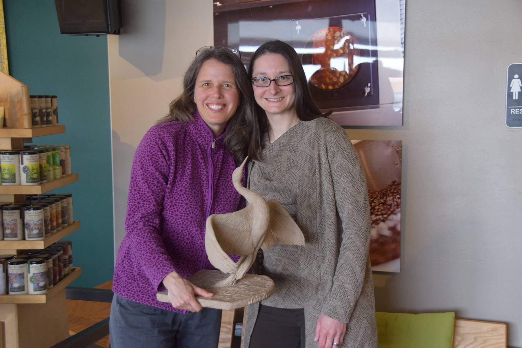 Artist Christina Demetro, left, and Shimai Toshi Garden Trails President Sarah Pyhala show off a rough model of Demetro’s 6-foot crane statue at Coffee Roasters in Soldotna on May Wednesday. (Photo by Brian Mazurek/Peninsula Clarion)