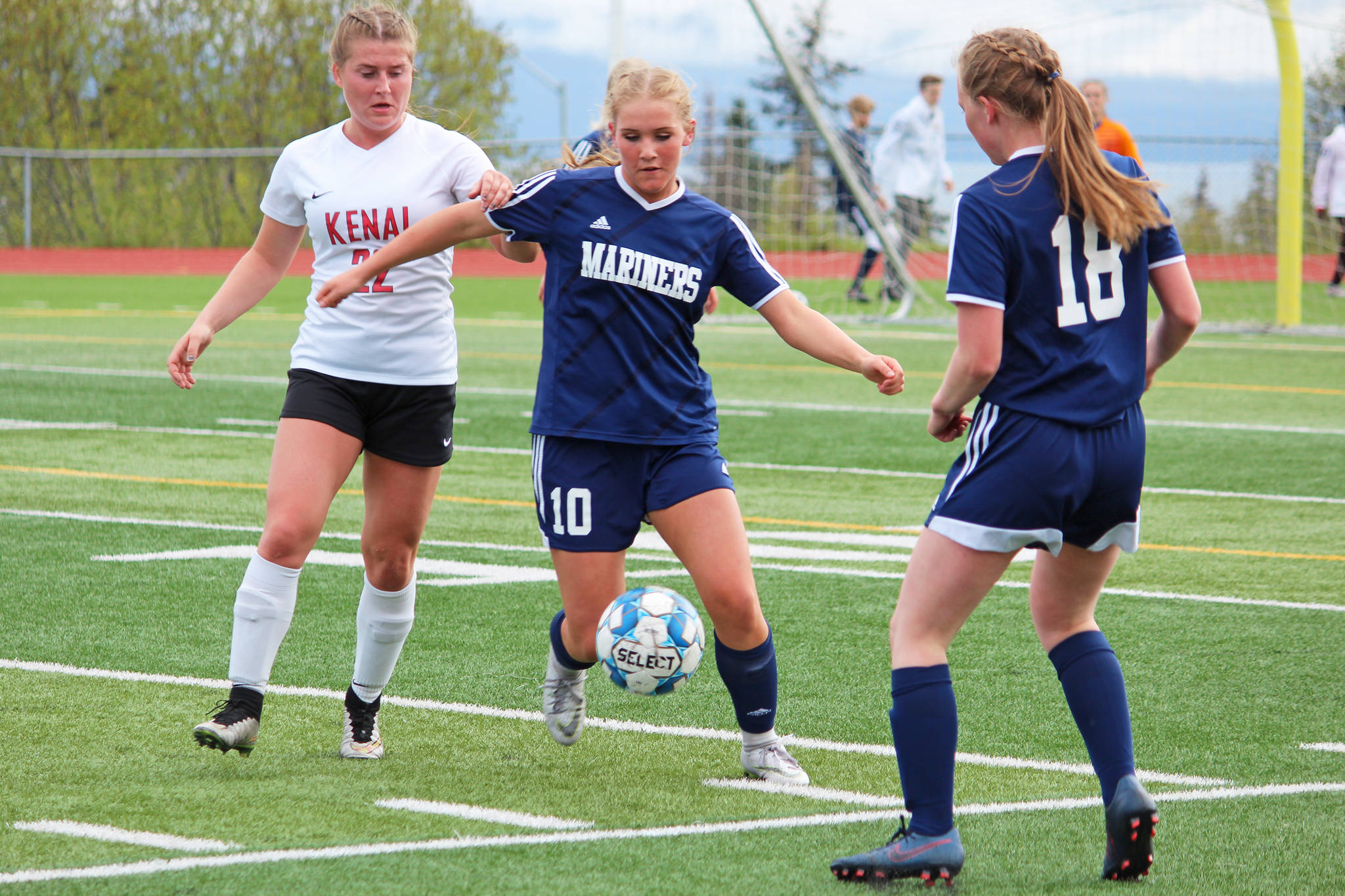 Homer’s Paige Jones (center) passes off the ball to teammate Zoe Stonorov (No. 18) under pressure from Kenai’s Olivia Brewer during the semi-final game of the Peninsula Conference Soccer Tournament on Friday, May 17, 2019 at Homer High School in Homer, Alaska. (Photo by Megan Pacer/Homer News)