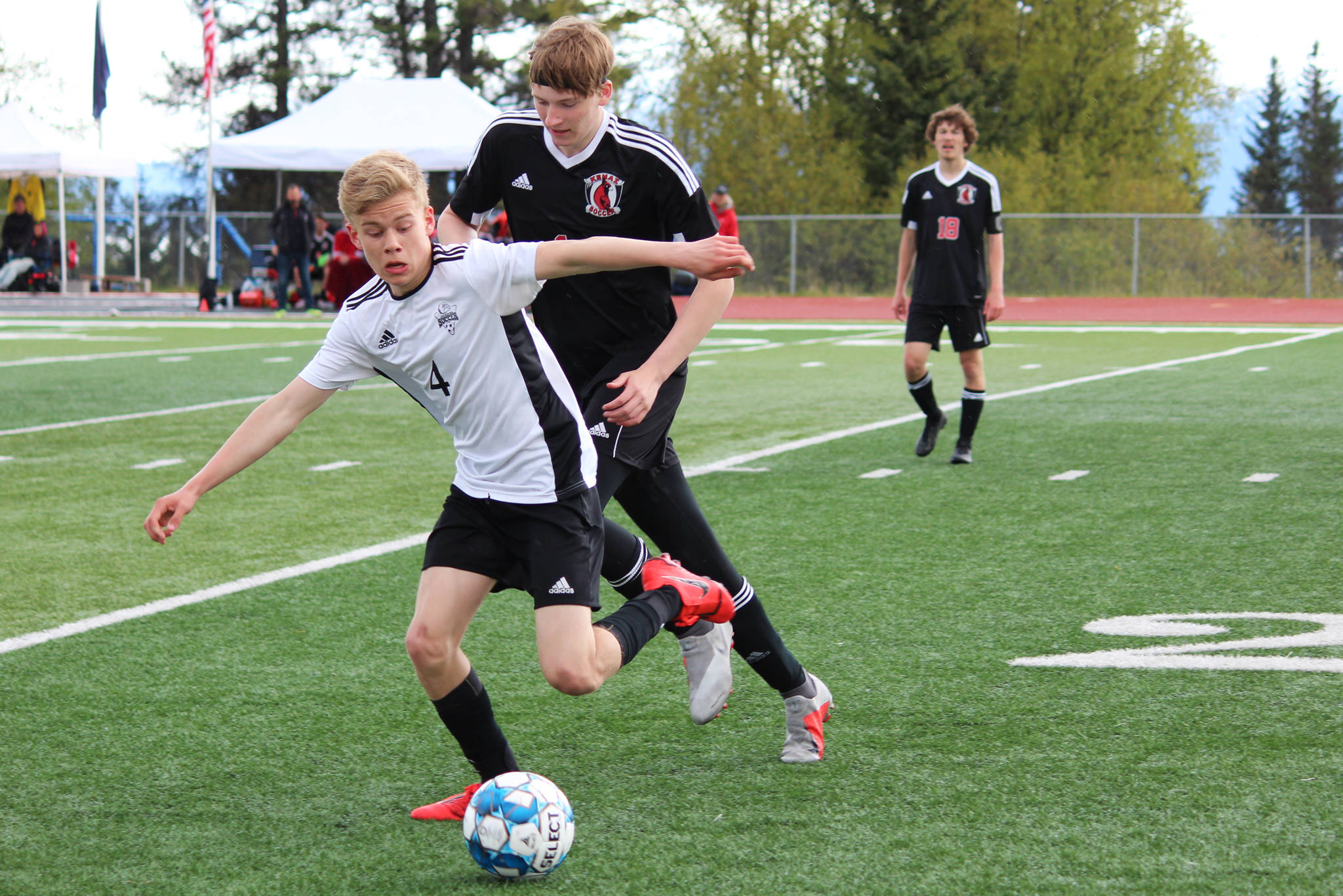 Nikiski’s Gavin White tries to keep control of the ball under pressure from Kenai’s Evan Stockton during a Peninsula Conference Soccer Tournament game Friday, May 17, 2019 at Homer High School in Homer, Alaska. Kenai advanced to the conference championship game on Saturday with a 3-0 win over the Bulldogs. (Photo by Megan Pacer/Homer News)