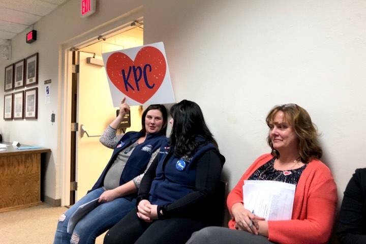 Kenai Peninsula College supporters hold a sign in the back of the Kenai Peninsula Borough Assembly Chambers at Tuesday’s meeting, May 21, 2019, in Soldotna, Alaska. (Photo by Victoria Petersen/Peninsula Clarion)