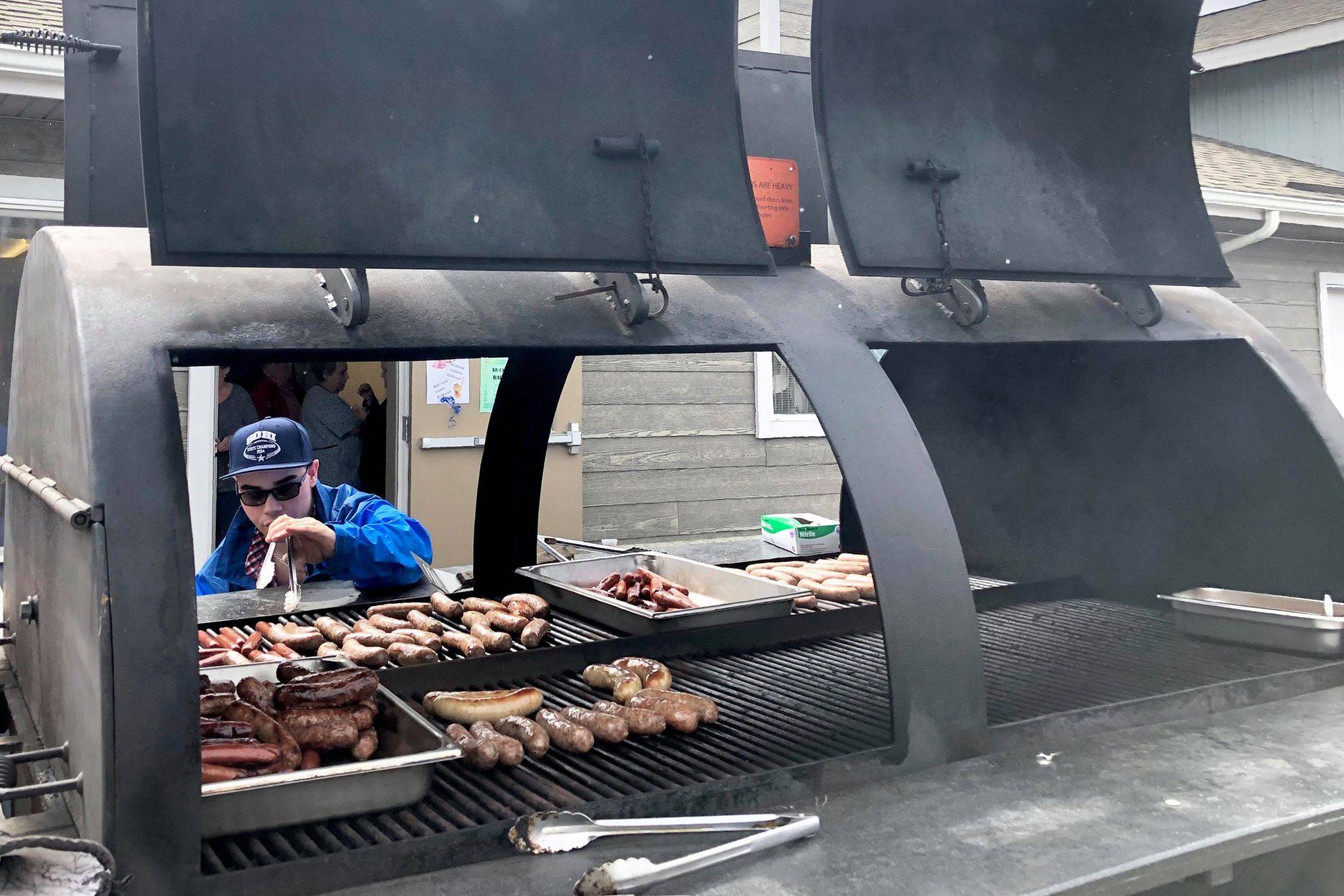 Matthew Martinelli, a volunteer at the Kenai Peninsula Food Bank Spring Festival and Fundraiser, helps cook brats and hot dogs for the event’s free picnic, Friday, May 31, 2019, near Soldotna, Alaska. (Photo by Victoria Petersen/Peninsula Clarion)