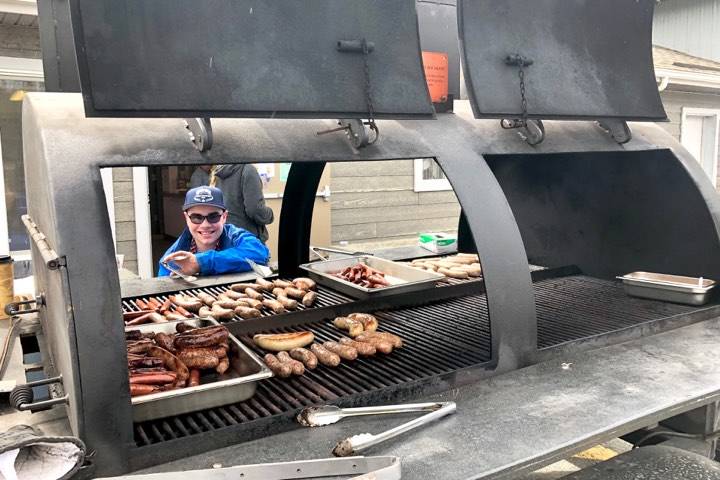 Matthew Martinelli, a volunteer at the Kenai Peninsula Food Bank Spring Festival and Fundraiser, helps cook brats and hot dogs for the event’s free picnic, Friday, May 31, 2019, near Soldotna, Alaska. (Photo by Victoria Petersen/Peninsula Clarion)
