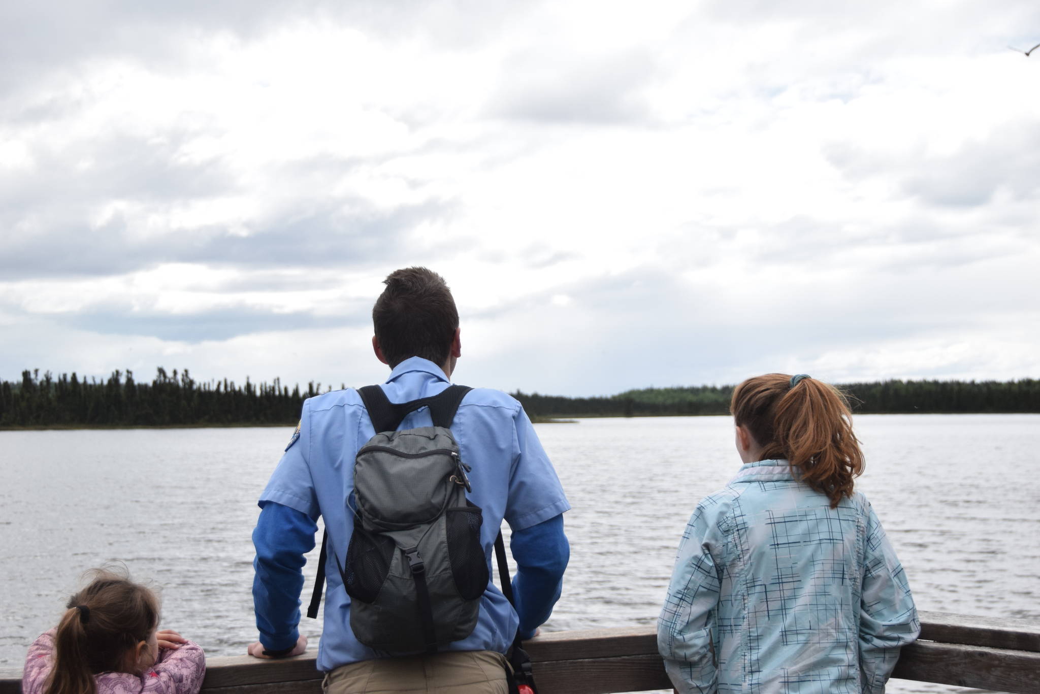 Annalynn Fay, left, David Fink, center, and Sasha Brott look out over Headquarters Lake during a guided hike on Centennial Trail in the Kenai National Wildlife Refuge on June 1, 2019. (Photo by Brian Mazurek/Peninsula Clarion)