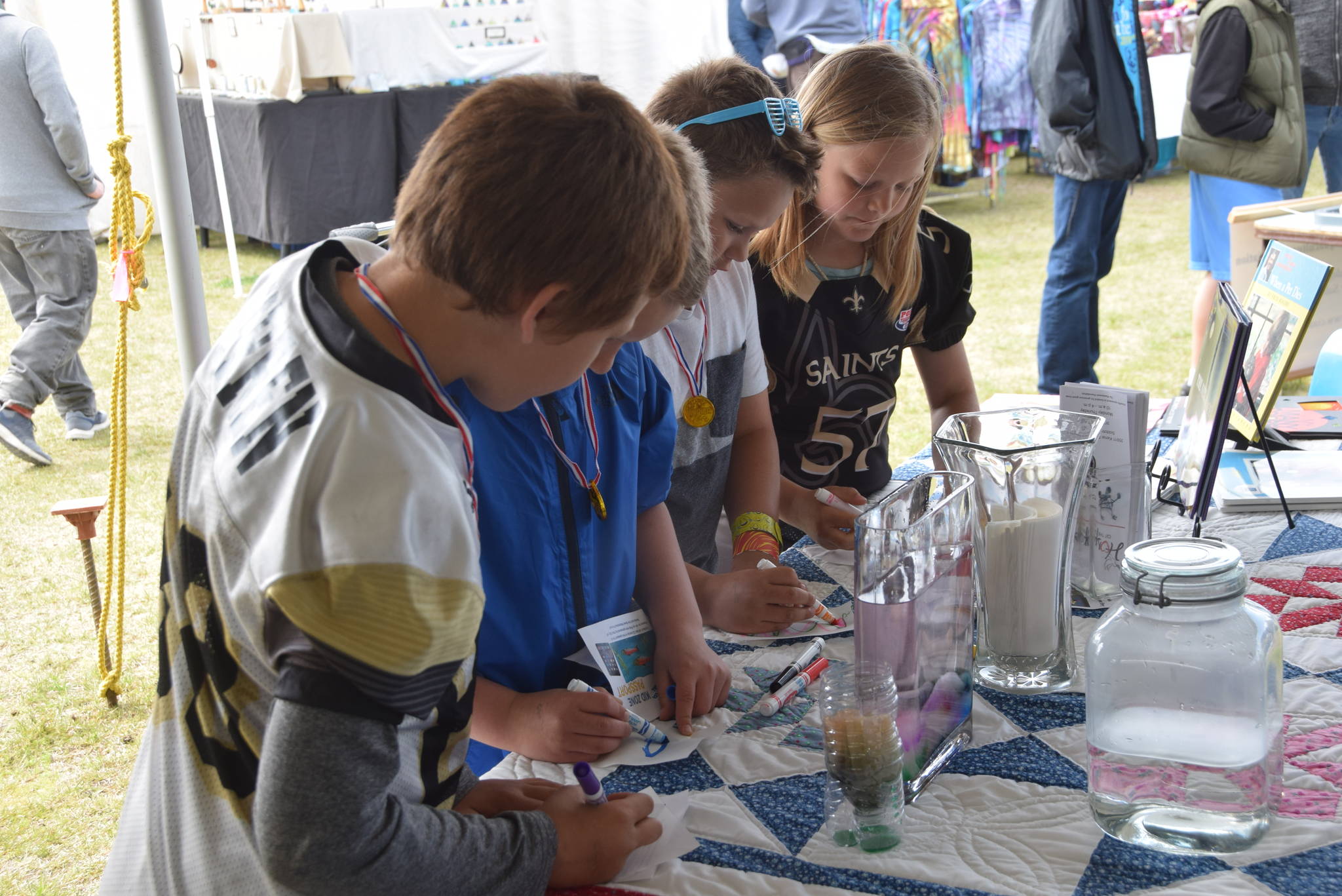 Kids color on sheets of rice paper that are then put into a container of water to show how pollutants get into rivers and other water sources during the Kenai River Festival at Soldotna Creek Park in Soldotna, Alaska on June 8, 2019. (Photo by Brian Mazurek/Peninsula Clarion)