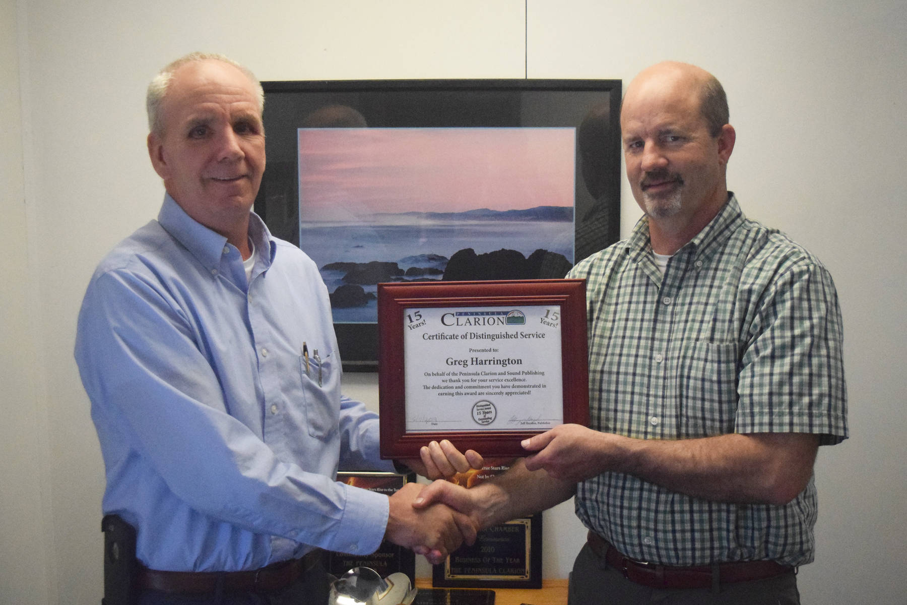 Peninsula Clarion publisher Jeff Hayden (left) congratulates Greg Harrington on 15 years of work at the newspaper. (Photo by Joey Klecka/Peninsula Clarion)