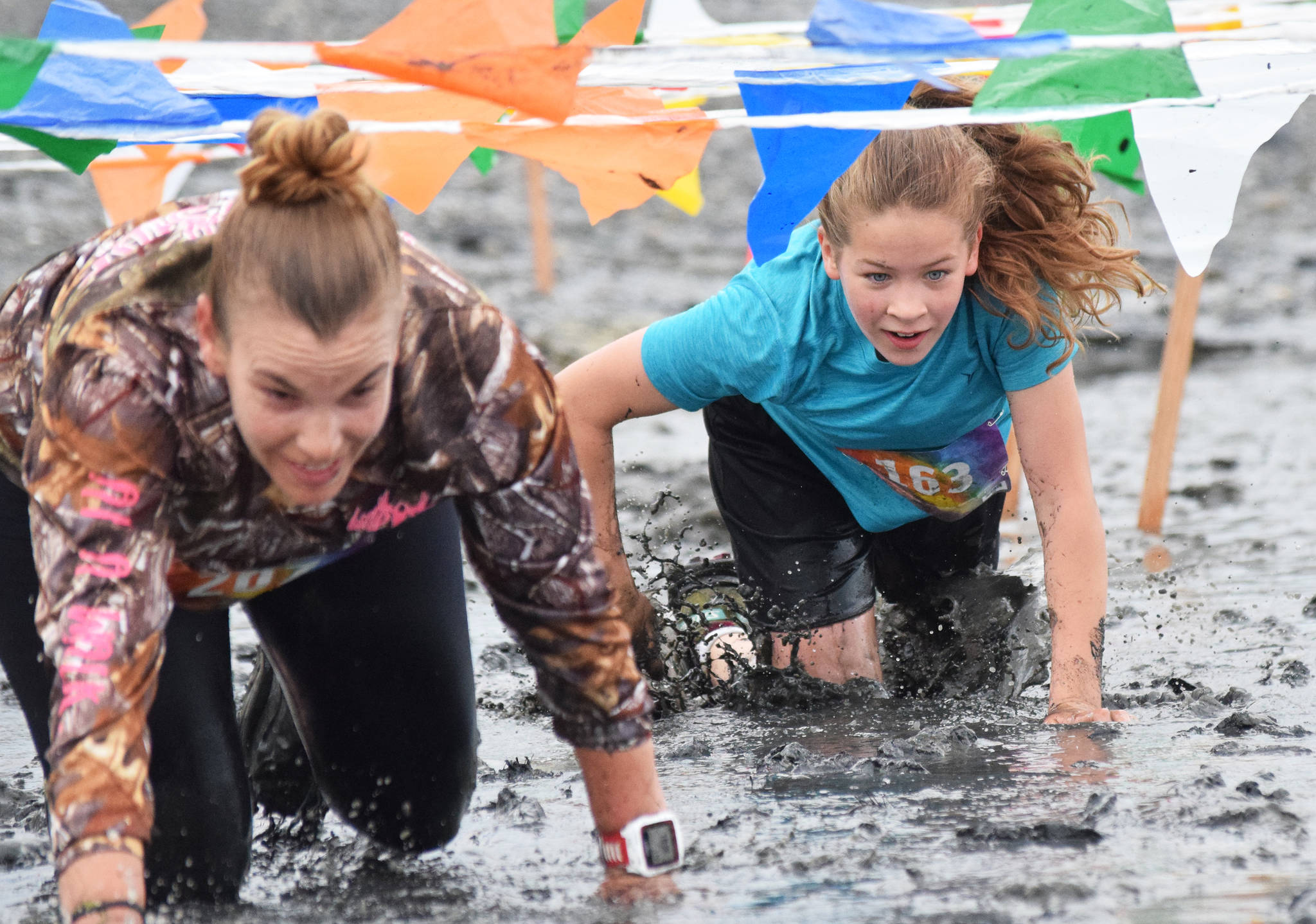 Teresa Fallon (right) follows Julie Mages through the mud Saturday, June 15, 2019, at the Ninilchik Clam Scramble Mud and Obstacle Run in Ninilchik, Alaska. (Photo by Joey Klecka/Peninsula Clarion)