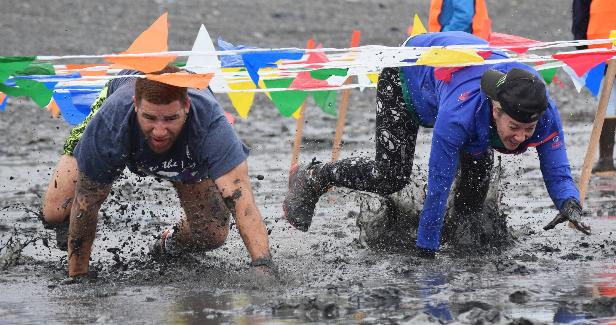 Jay Harris (left) and Megan Anderson race through the mud Saturday, June 15, 2019, at the Ninilchik Clam Scramble Mud and Obstacle Run in Ninilchik, Alaska. (Photo by Joey Klecka/Peninsula Clarion)