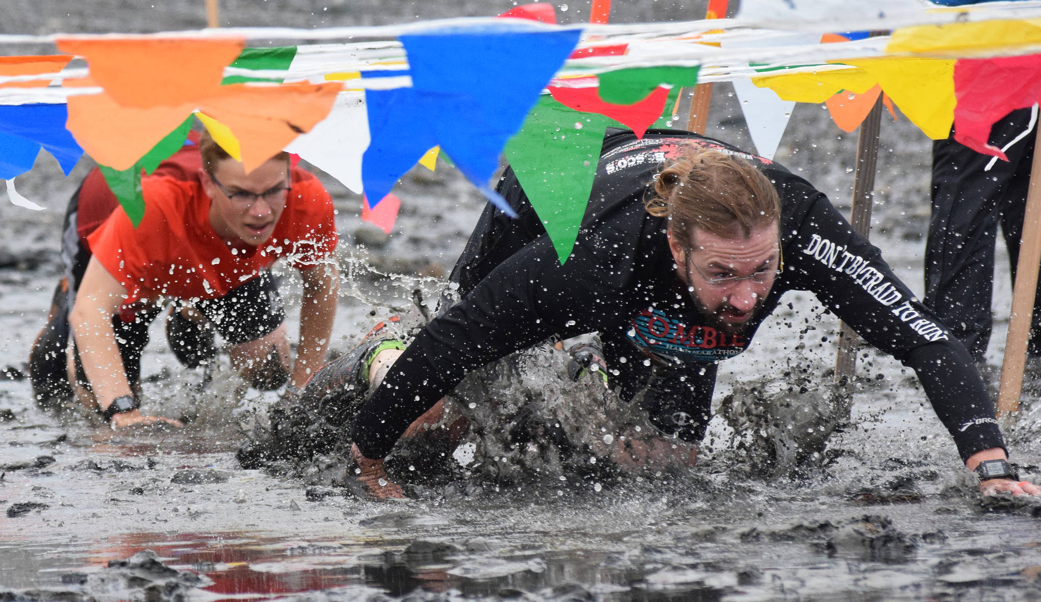 Zachary Ricketts (right) leads Tyler Hippchen through the mud Saturday, June 15, 2019, at the Ninilchik Clam Scramble Mud and Obstacle Run in Ninilchik, Alaska. (Photo by Joey Klecka/Peninsula Clarion)