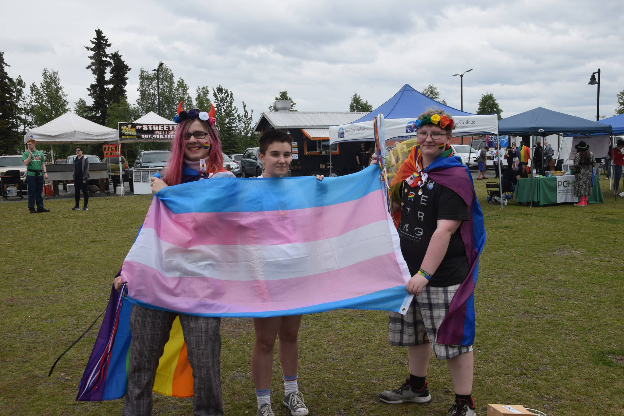 From left, Timmy Opheim, Jacey Kosto and Charlie Rogers hold up the Trans Pride Flag during the 2019 Soldotna Pride Celebration in Soldotna Creek Park on Saturday, June 15, 2019. (Photo by Brian Mazurek/Peninsula Clarion)
