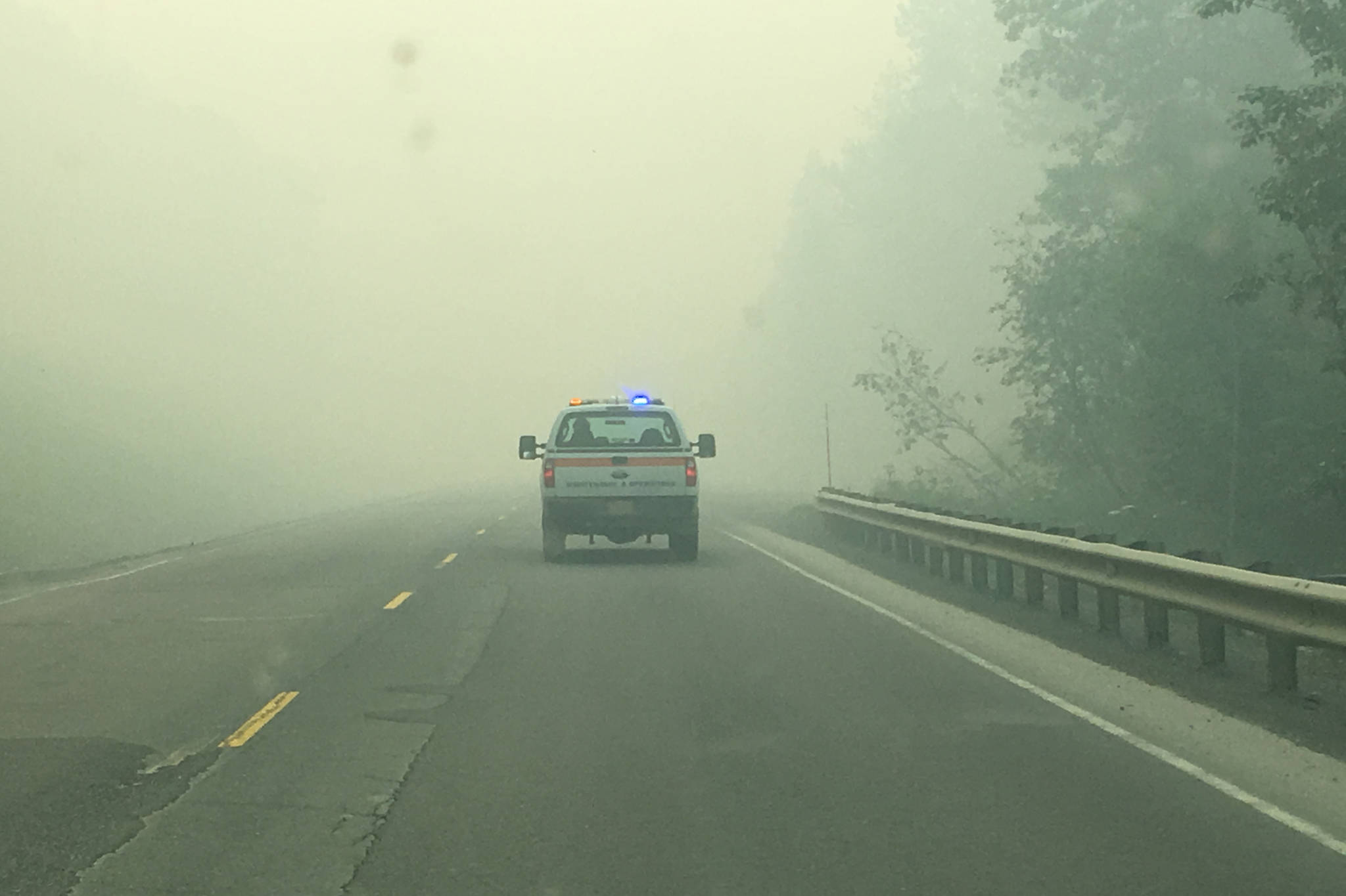 A service vehicle travels along the Sterling Highway on Wednesday, June 26, 2019, on Alaska’s Kenai Peninsula. The highway was closed for several hours Wednesday morning due to the Swan Lake Fire burning north of the highway.