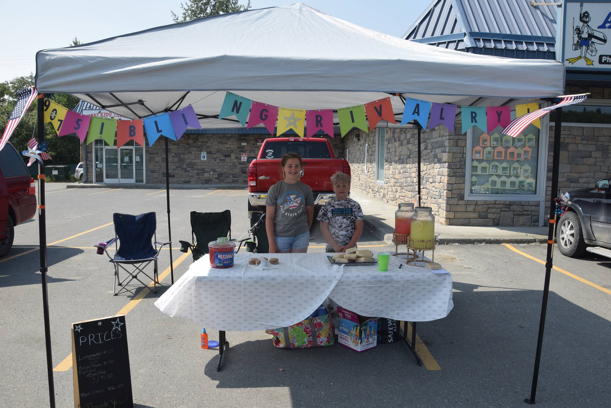 Avery Powell, left, and Nathan Powell, right, smile for the camera at their lemonade stand outside of Kenai Kids Therapy during Lemonade Day in Soldotna, Alaska on June 29, 2019. (Photo by Brian Mazurek/Peninsula Clarion)