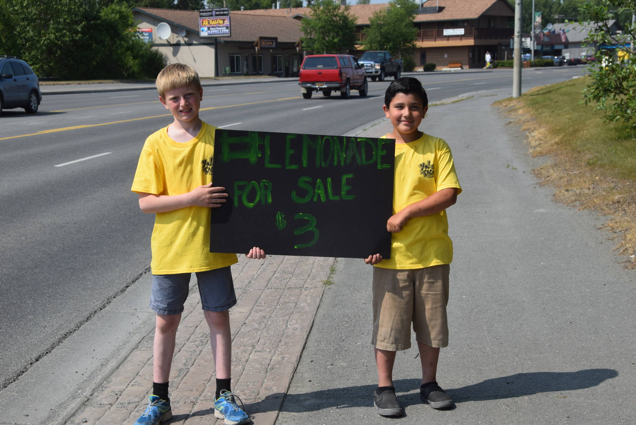 Tucker Challans, left, and Logan Amaya, right, advertise their lemonade business along the Kenai Spur Highway during Lemonade Day in Soldotna, Alaska on June 29, 2019. (Photo by Brian Mazurek/Peninsula Clarion)