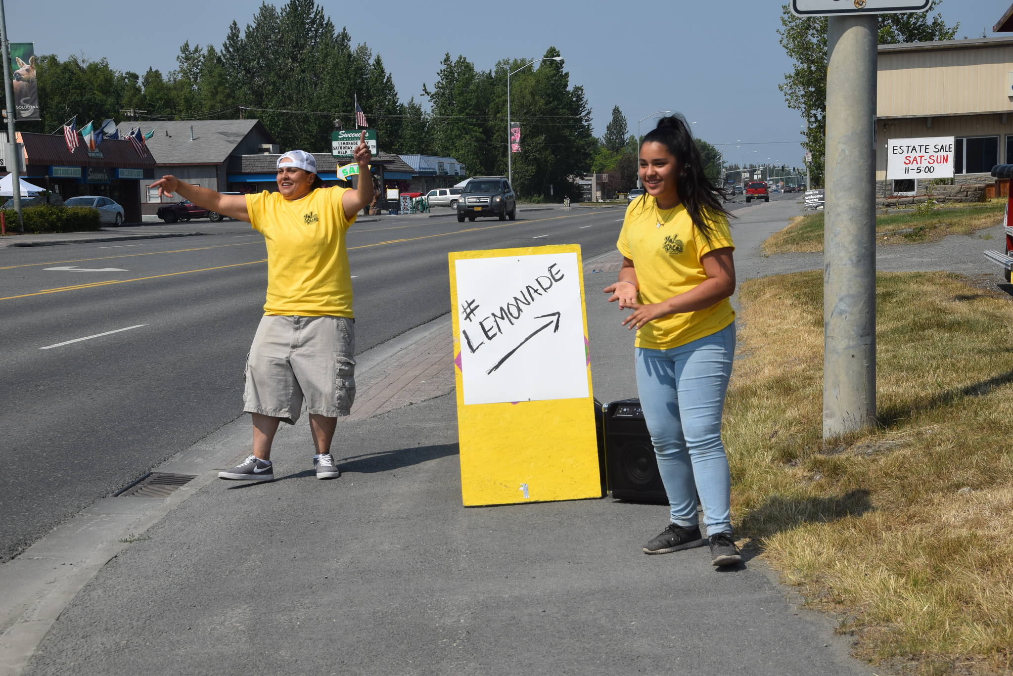 Nila Sanchez, left, and Alexa Menzel, right, advertise their lemonade business along the Kenai Spur Highway during Lemonade Day in Soldotna, Alaska on June 29, 2019. (Photo by Brian Mazurek/Peninsula Clarion)
