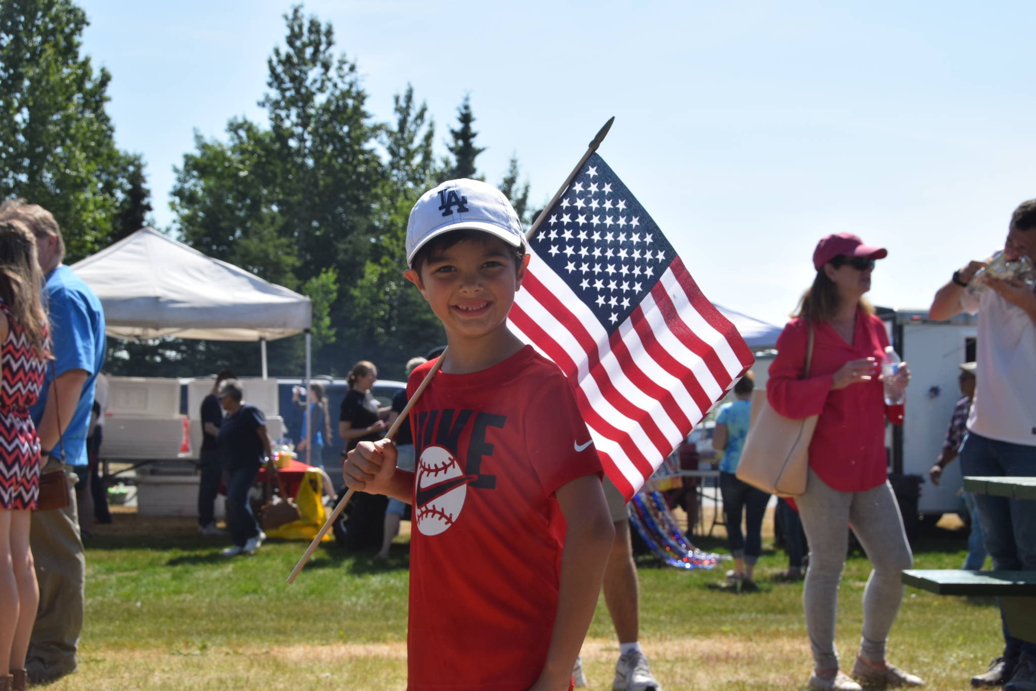 Reagan Reed poses with an American flag at the Kenai Park Strip during the July 4th parade in Kenai, Alaska. (Photo by Brian Mazurek/Peninsula Clarion)