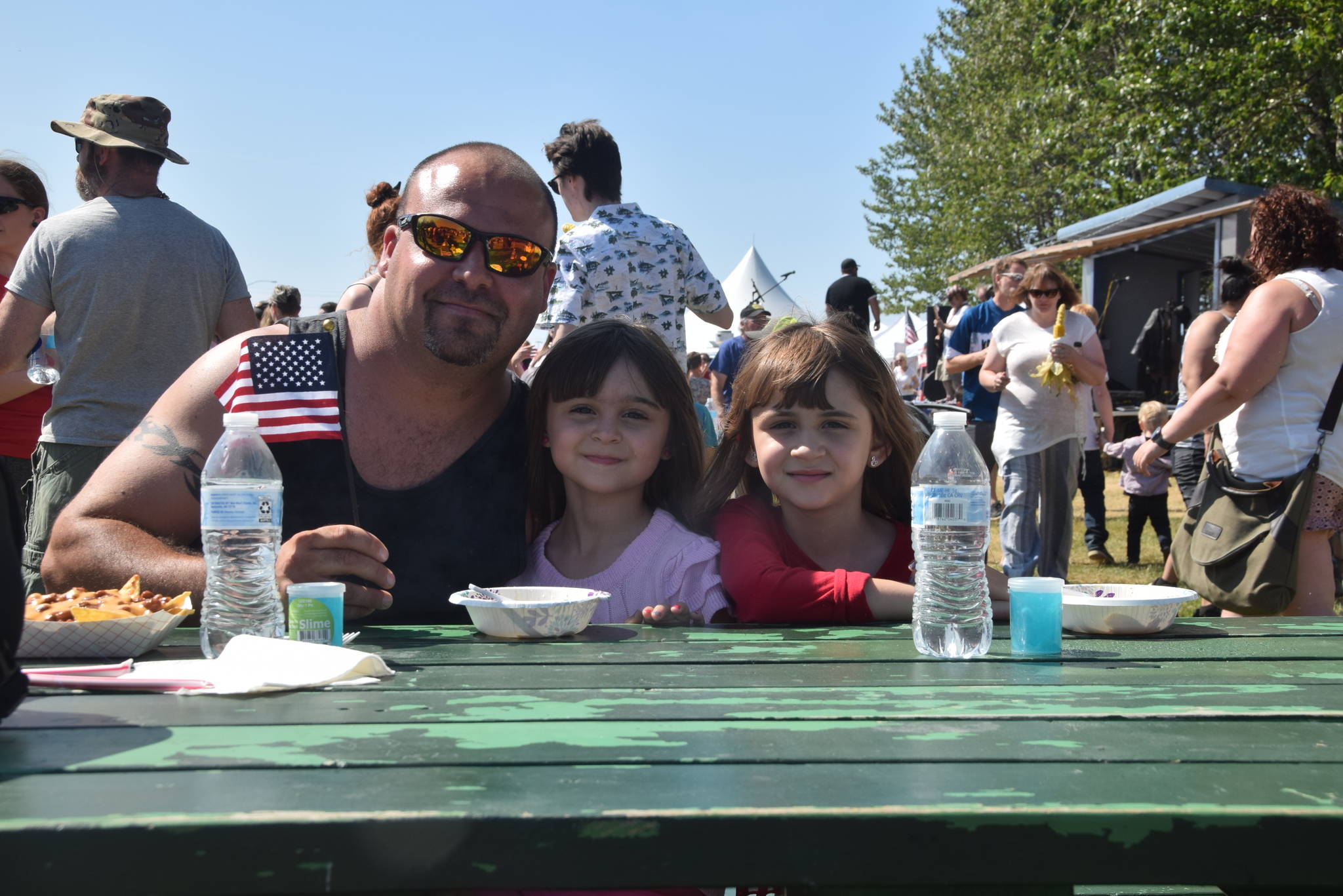 Stan Holguin and his daughters Lilliana and Jaelyn smile for the camera at the Kenai Park Strip during the July 4th parade in Kenai, Alaska. (Photo by Brian Mazurek/Peninsula Clarion)