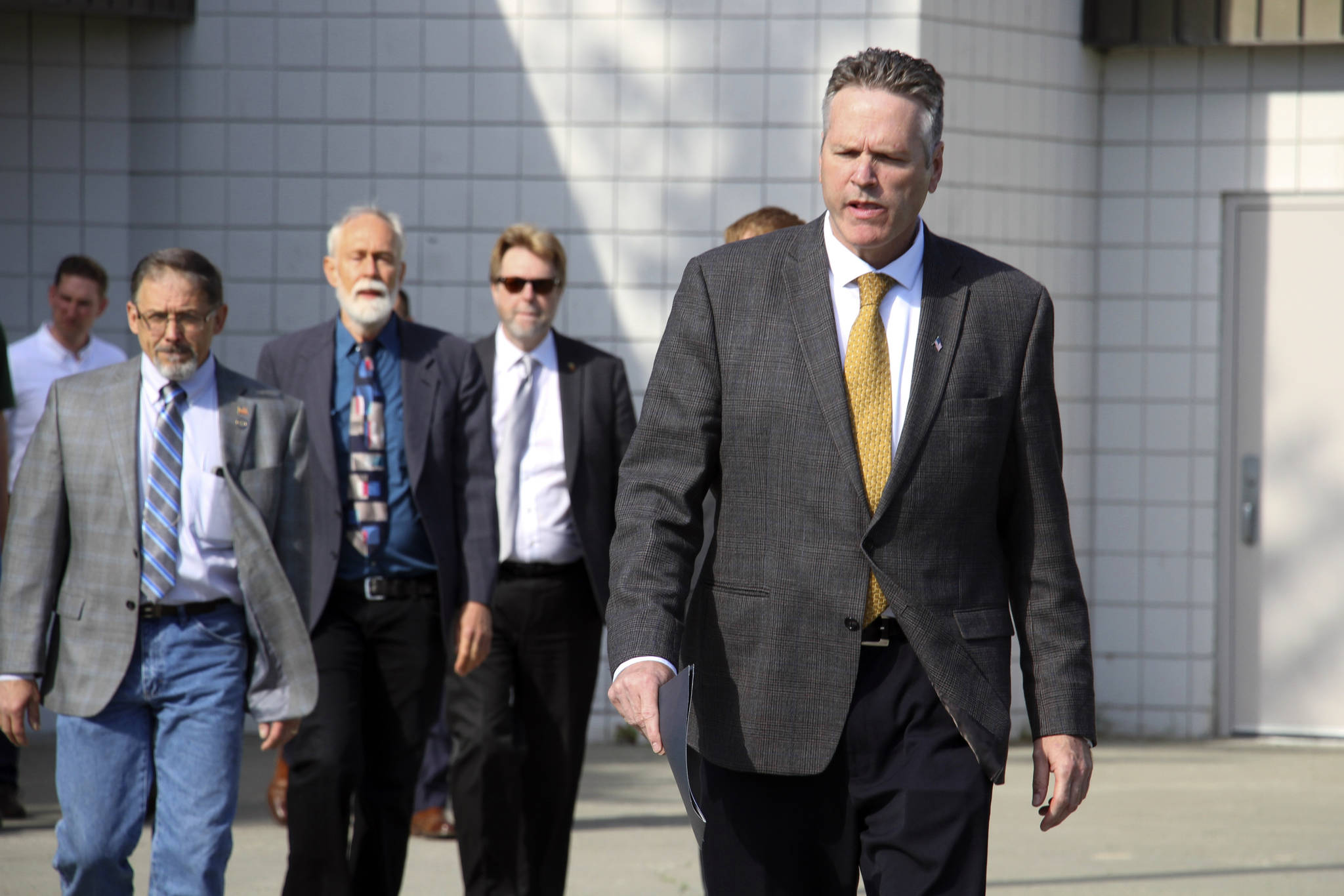 This June 14, 2019 file photo shows Alaska Gov. Mike Dunleavy leading state and local officials out of Wasilla Middle School in Wasilla, Alaska, to a news conference. State lawmakers have rejected Dunleavy’s suggested location for a special session. House Speaker Bryce Edgmon and Senate President Cathy Giessel issued a joint statement Monday, June 24, 2019 saying they will convene July 8 in Juneau and hold most hearings in Anchorage. Dunleavy had called the session for Wasilla, his hometown and conservative base.(AP Photo/Mark Thiessen, File)