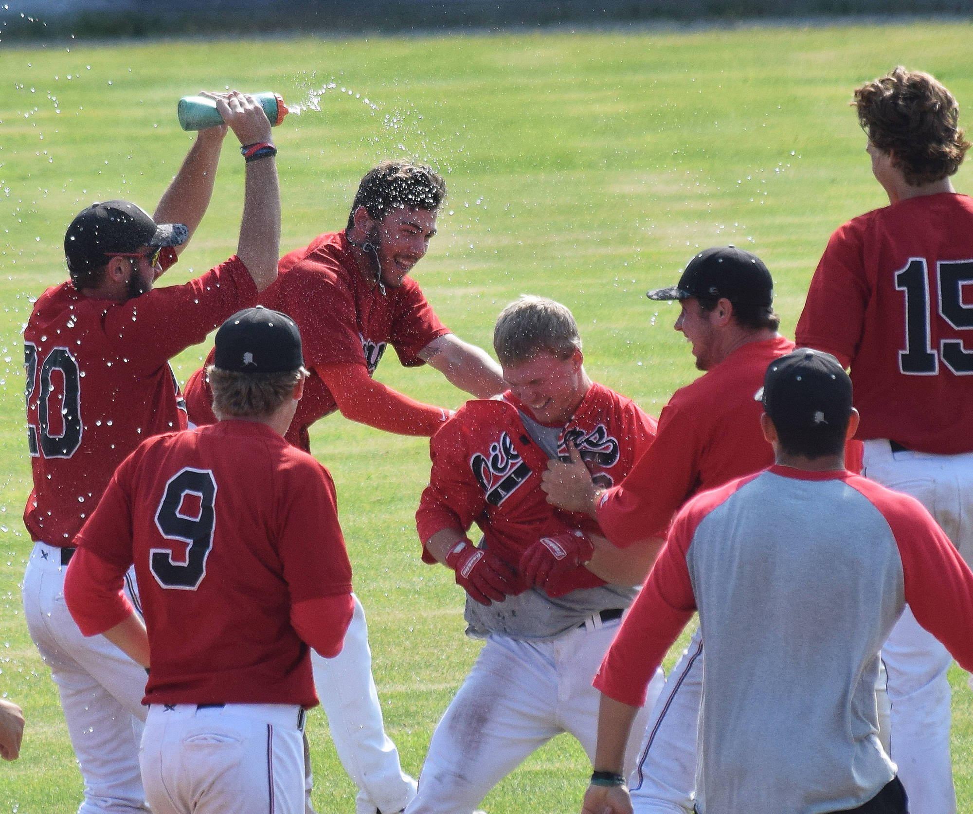Peninsula Oilers outfielder Paul Steffensen (center) is mobbed by teammates after delivering the game-winning play Sunday, July 7, 2019, against the Mat-Su Miners at Coral Seymour Memorial Park in Kenai, Alaska. (Photo by Joey Klecka/Peninsula Clarion)