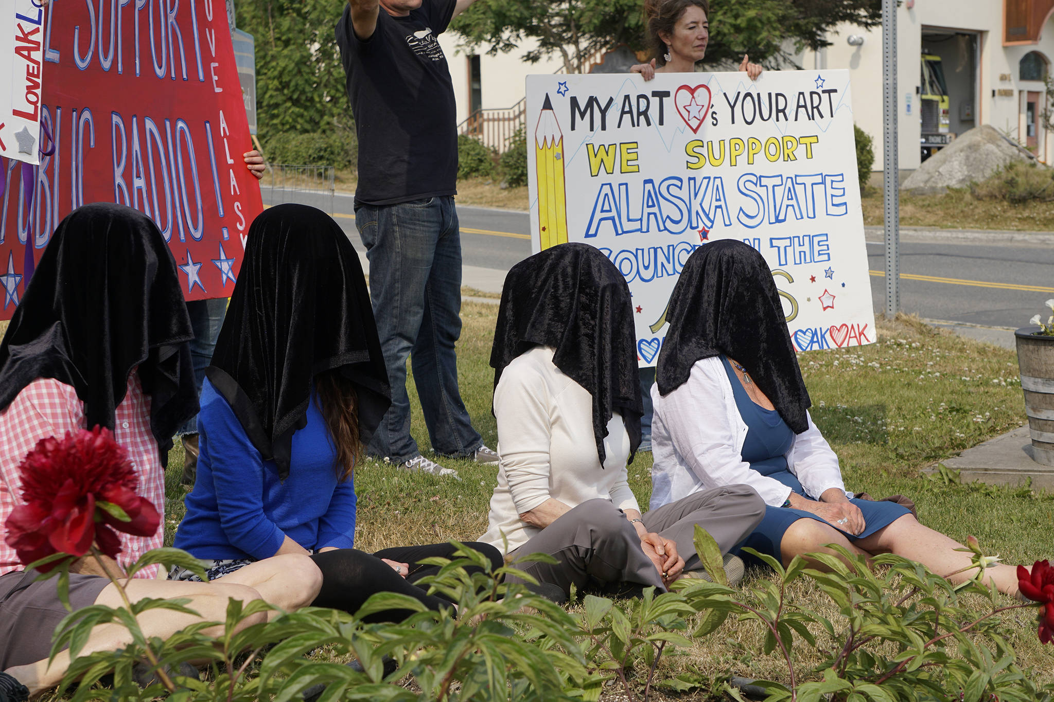 Photo by Michael Armstrong / Homer News                                Women draped in black sit down Tuesday at WKFL Park in Homer as part of a statewide art intervention to protest Gov. Mike Dunleavy’s veto of a $2.8 million state appropriation to the Alaska State Council on the Arts. They also supported a general override of Dunleavy’s vetoes that will affect funding for the University of Alaska, public radio and other programs.