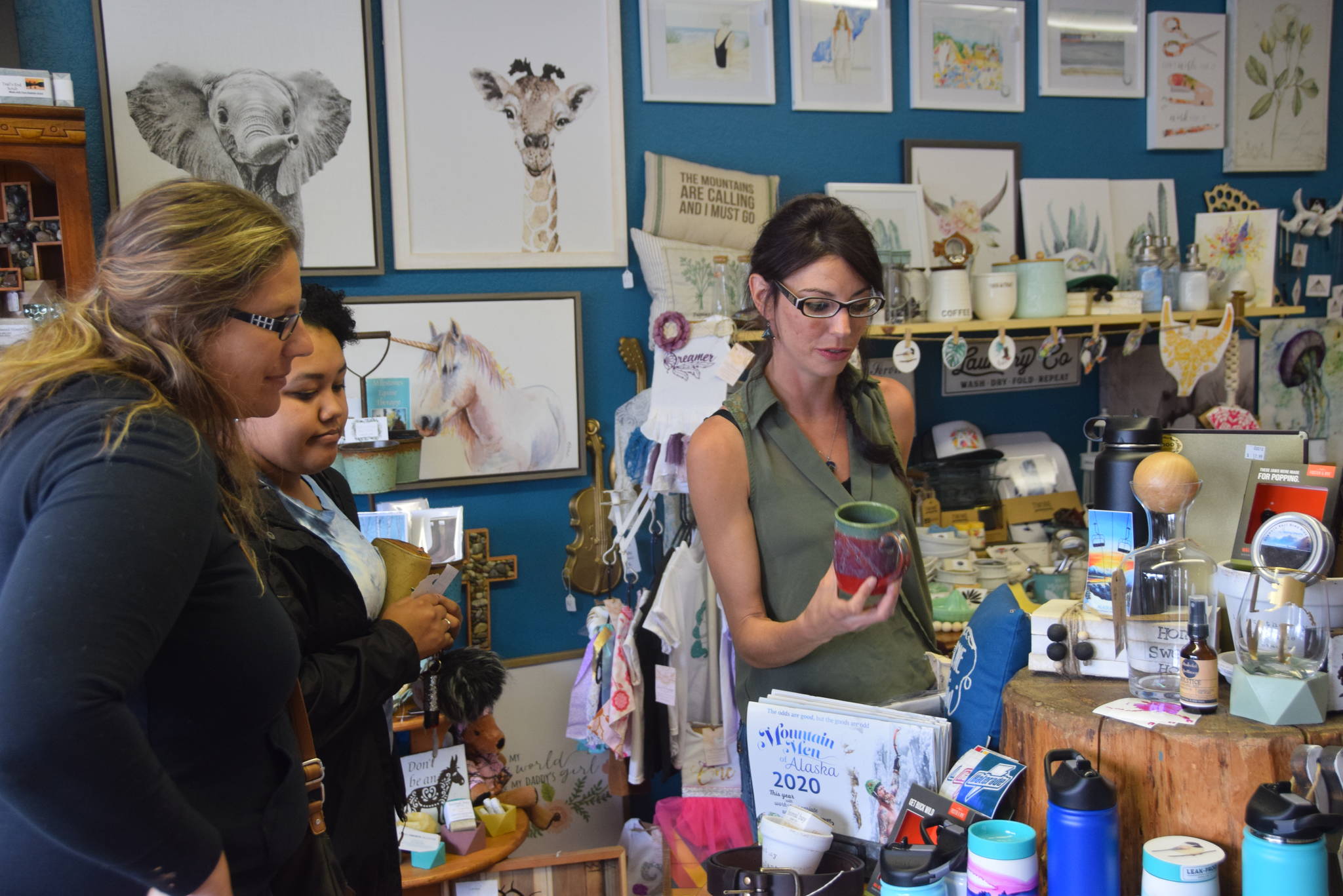 Localz owner Angel Stanton, right, shows Heidi Vann, left, and Denali Jackson, center, some of the products featured in her store on July 11, 2019 in Nikiski, Alaska. (Photo by Brian Mazurek/Peninsula Clarion)