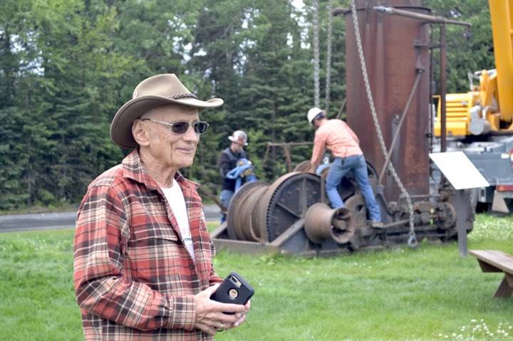 Dr. Peter Hansen stands in front of crane operators who are in the process of lifting an antique steam donkey engine at the Kenai Visitor and Cultural Center, where it will be relocated on the lawn to make room for a cabin that will act as a Kenai Bush doctors museum, Monday, July 15, 2019, in Kenai, Alaska. (Photo by Victoria Petersen/Peninsula Clarion)