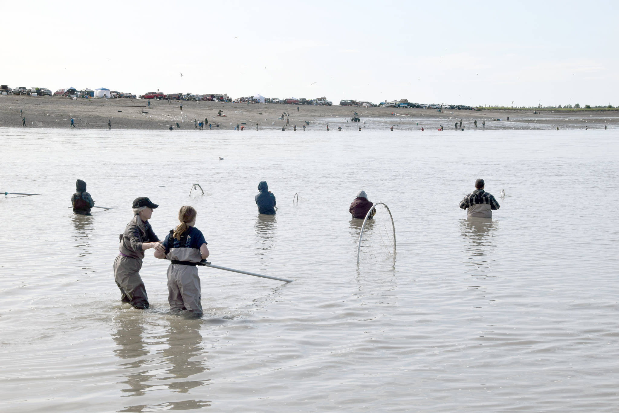 Claudia Henley, front left, shows her grandson Austin Feagin a few tips while dipnetting on the North Kenai Beach on Wednesday, July 17, 2019. (Photo by Brian Mazurek/Peninsula Clarion)