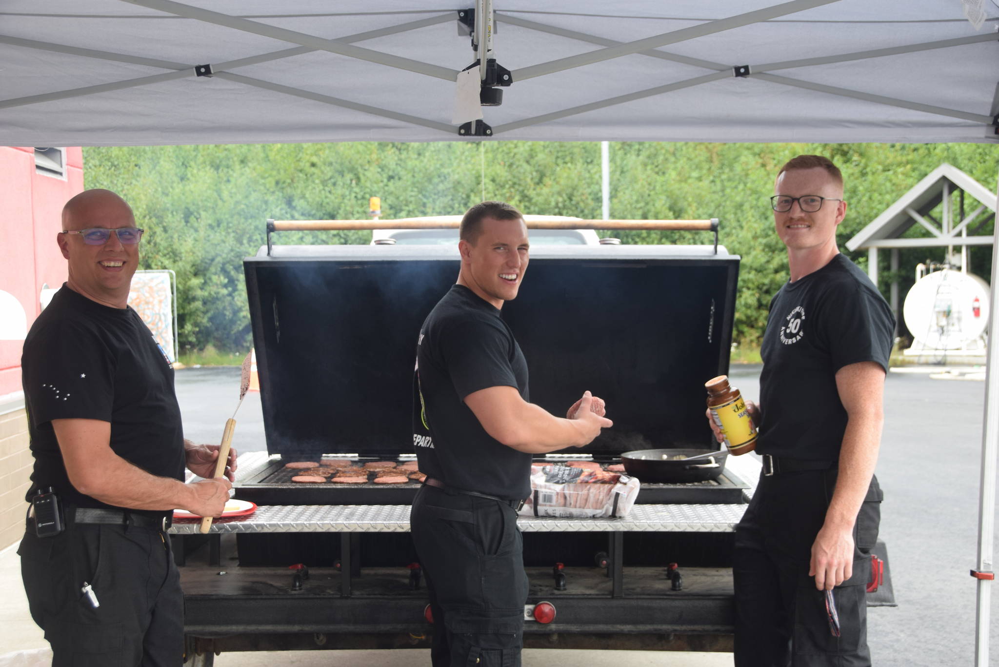 From left, Firefighters Jason Tauriainen, Stephen Hartley and Jesse Ross man the grill at Fire Station #2 during the Nikiski Fire Department’s 50th anniversary celebration in Nikiski, Alaska on July 15, 2019. (Photo by Brian Mazurek/Peninsula Clarion)
