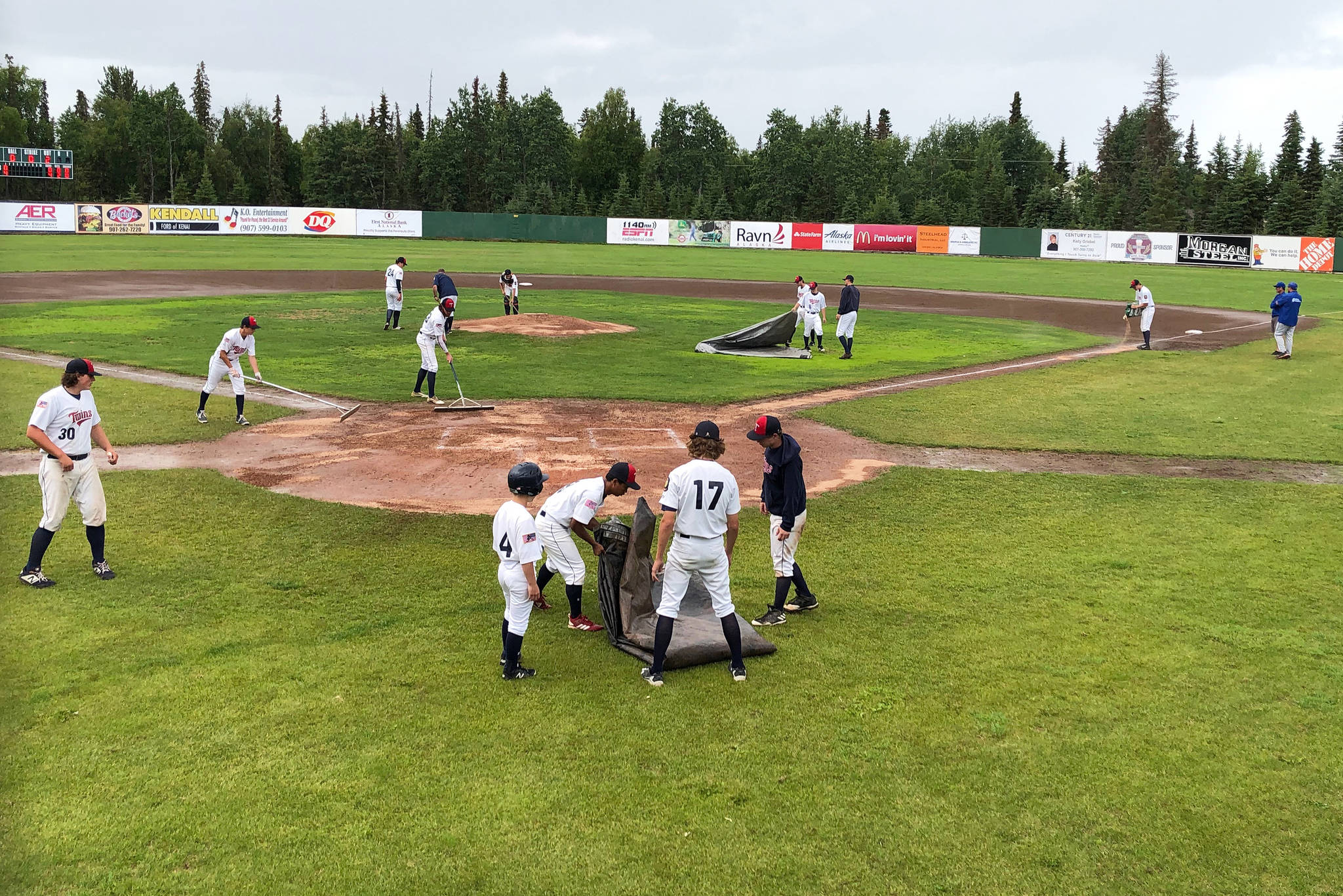 Members of the Legion Twins work to dry the infield after a brief shower Tuesday, July 16, 2019, at Coral Seymour Memorial Park in Kenai, Alaska. (Photo by Joey Klecka/Peninsula Clarion)