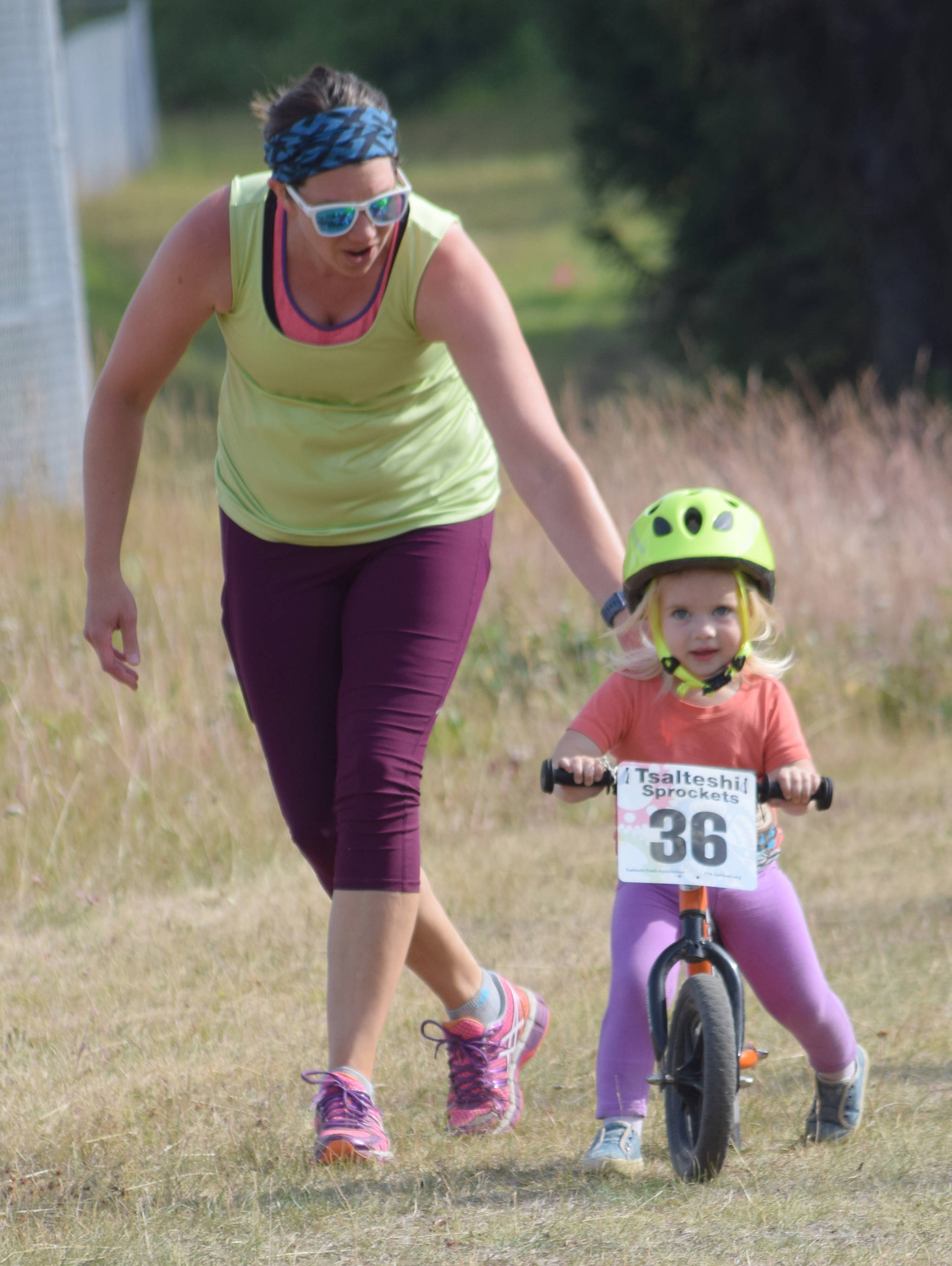 Angie Nelson of Kenai helps her daughter, Clara, 2, to the finish line in the kids ramble Thursday, July 18, 2019, at Tsalteshi Trails. (Photo by Jeff Helminiak/Peninsula Clarion)