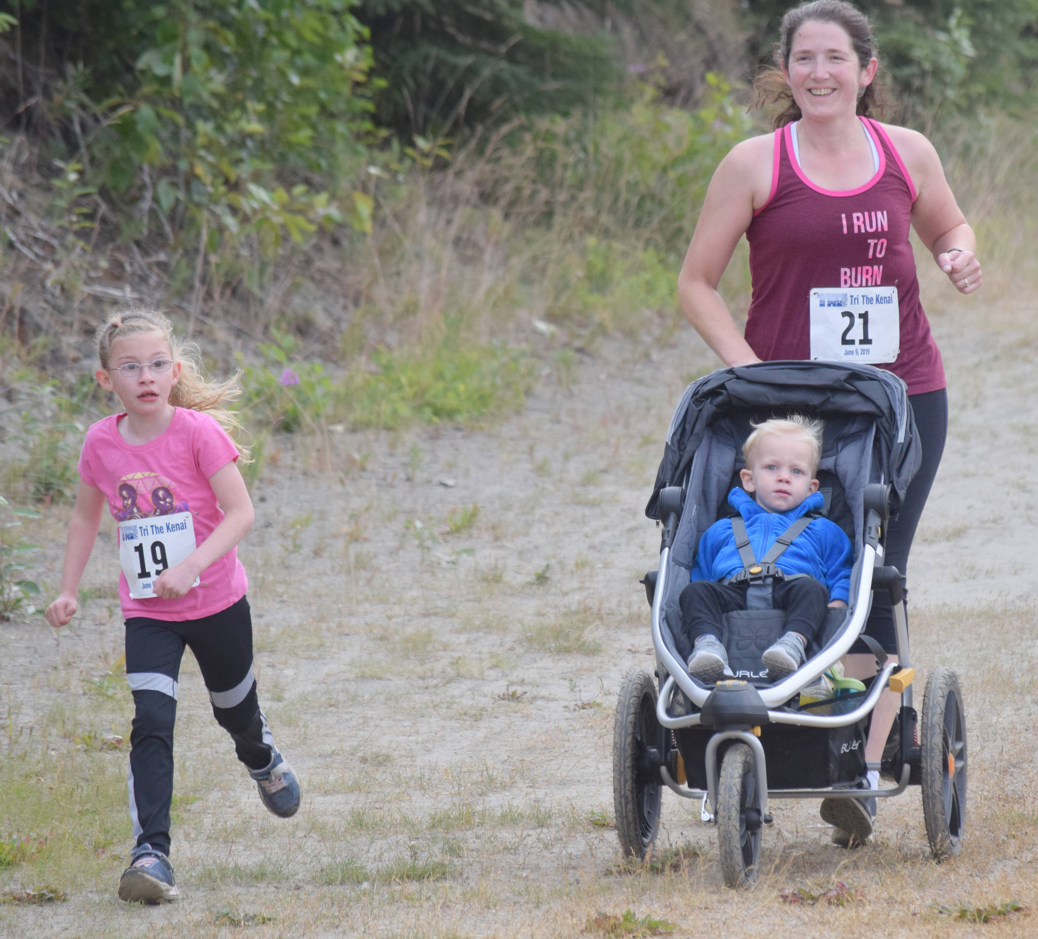 Denali Tucker, 7, of Soldotna leads her mother, Kandi Barcus, and brother, Justice Tucker, 2, in the Rotary Unity Run on Saturday, July 20, 2019, at Tsalteshi Trails. (Photo by Jeff Helminiak/Peninsula Clarion)